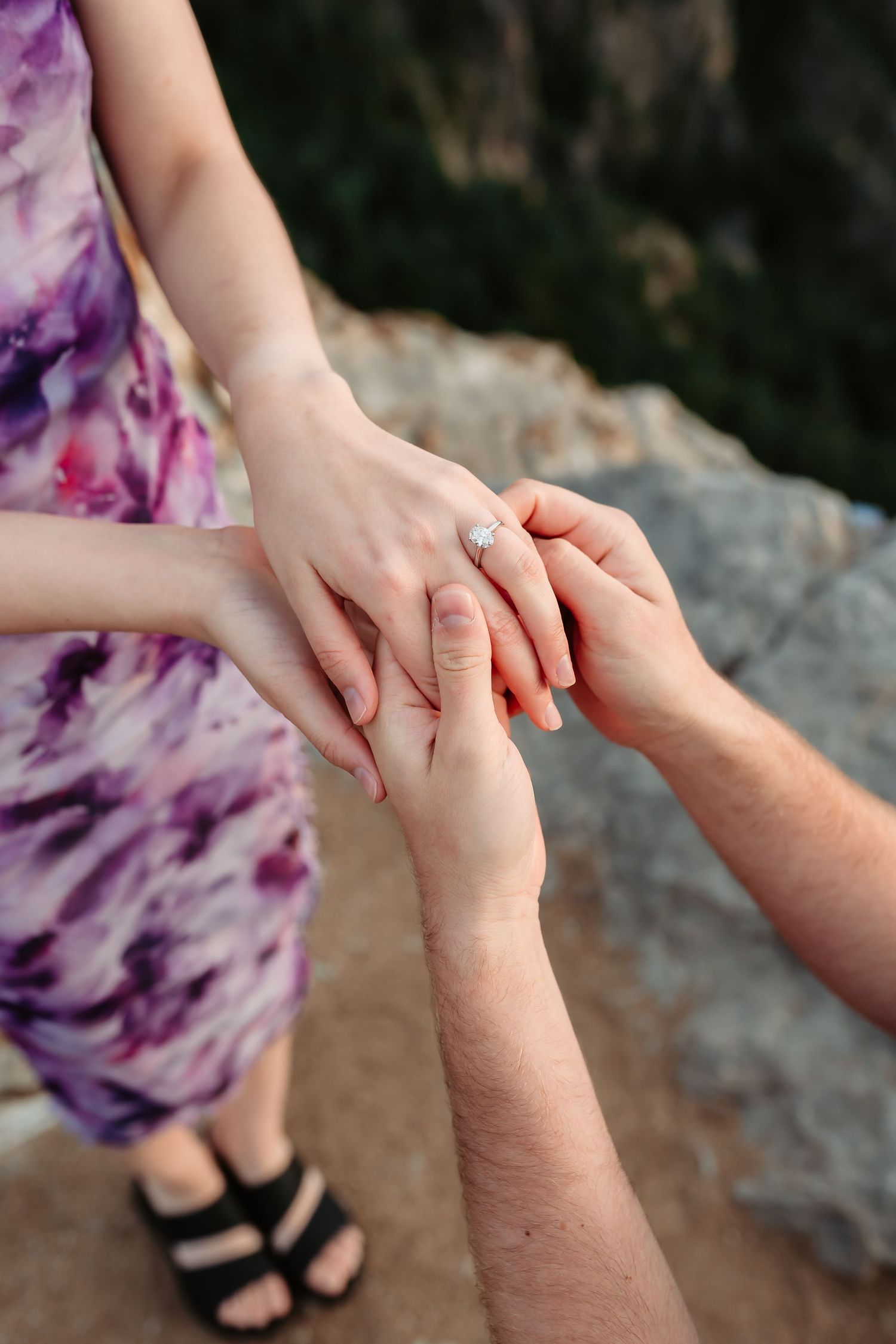 A close-up shot of hands during a proposal moment with a purple tie-dye dress visible.