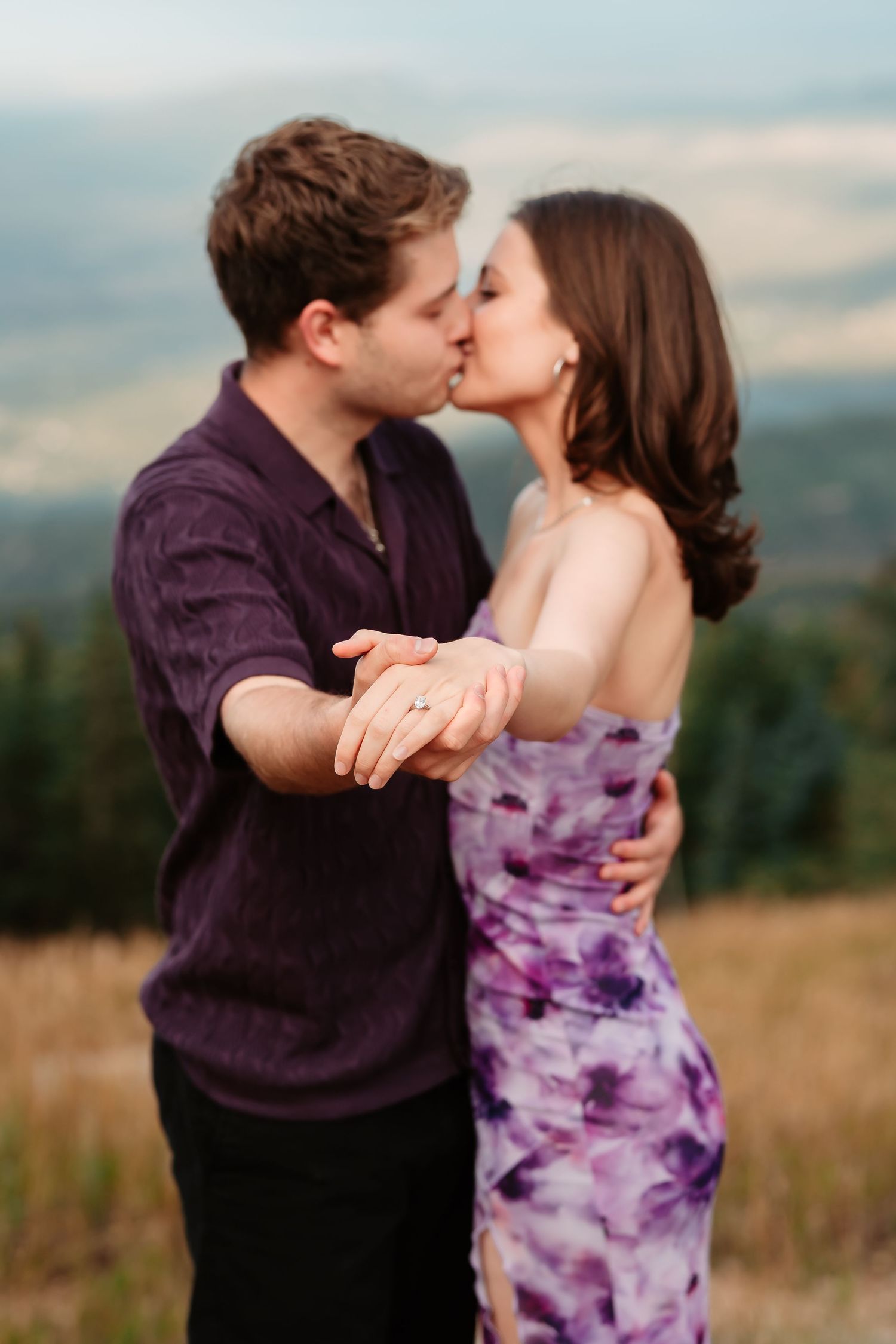 Romantic outdoor engagement photos at sunset showing couple in purple clothing sharing an intimate kiss in a field.