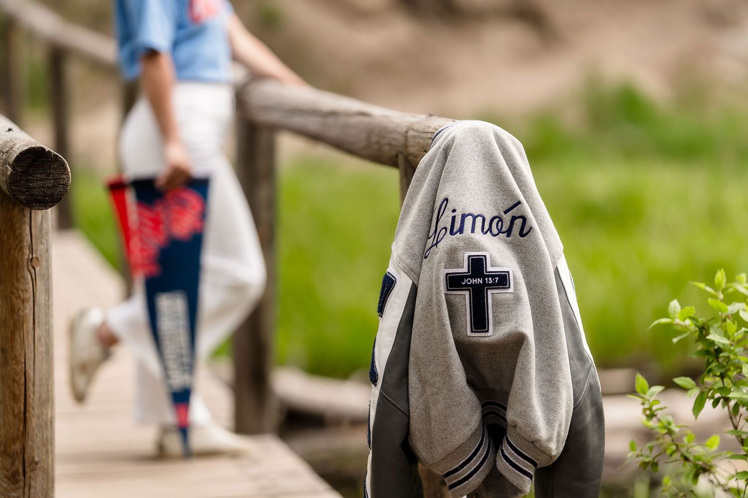 Gray Simon cross embroidered shirt draped over wooden railing on a bridge path.