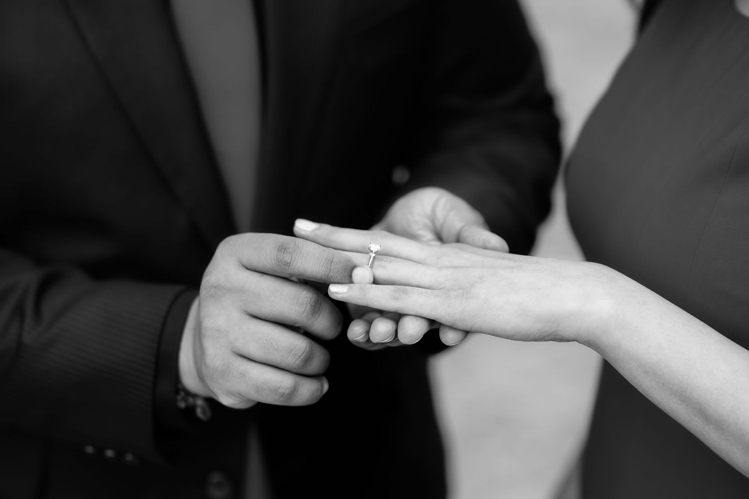 Close-up of hands exchanging rings during an engagement or wedding moment.