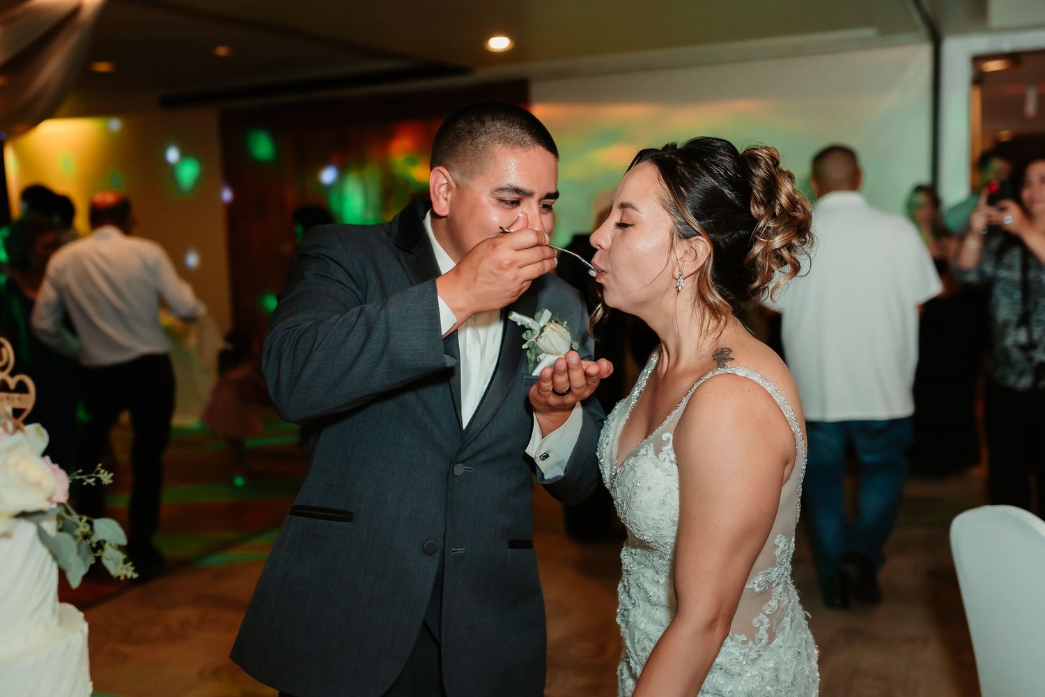 Joyful couple shares a sweet moment while tasting their wedding cake.