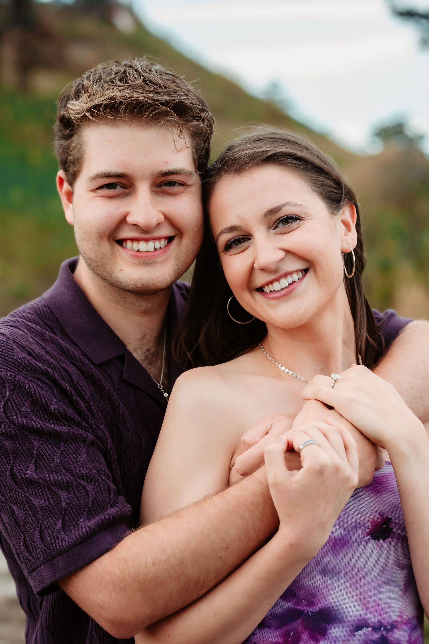 A couple shares loving embraces while wearing purple attire during a romantic outdoor photo shoot.