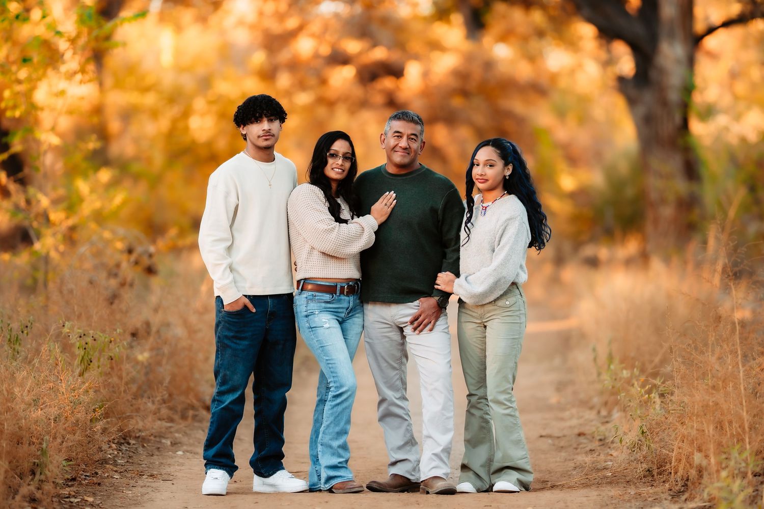 A group of people walking together on a nature trail during golden hour with autumn foliage in the background.