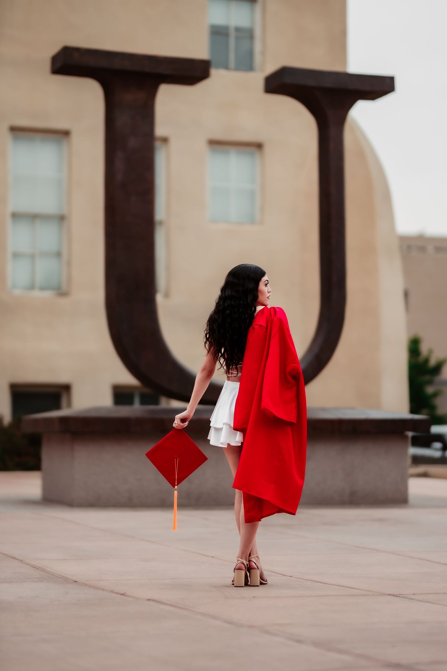 A series of minimalist photos showing a red graduation gown floating against beige architecture and concrete.