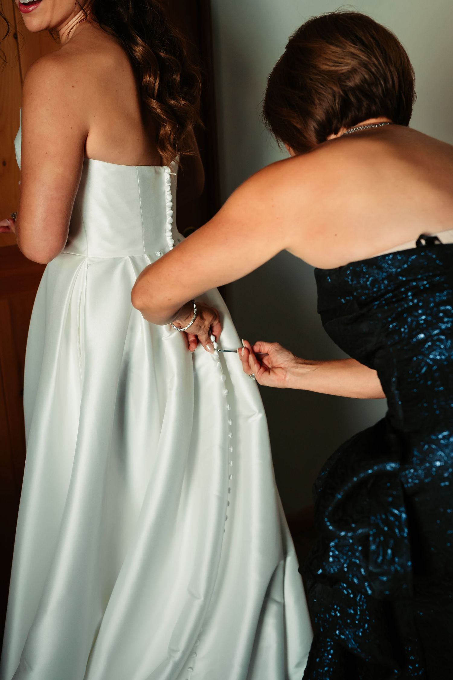 A series of photos showing someone helping button up a white wedding dress from behind.