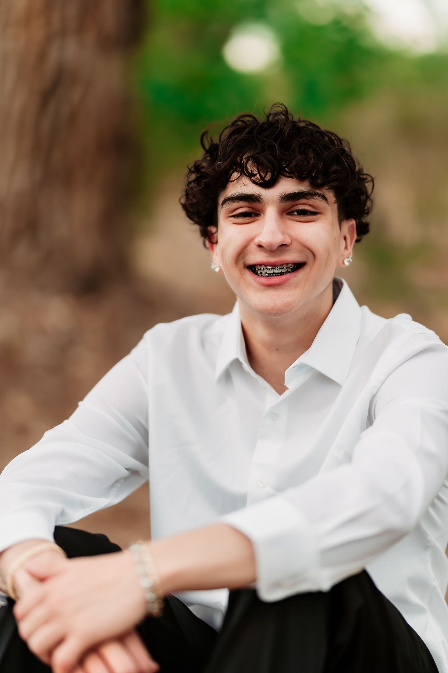 Portrait of someone in a crisp white button-down shirt sitting outdoors.
