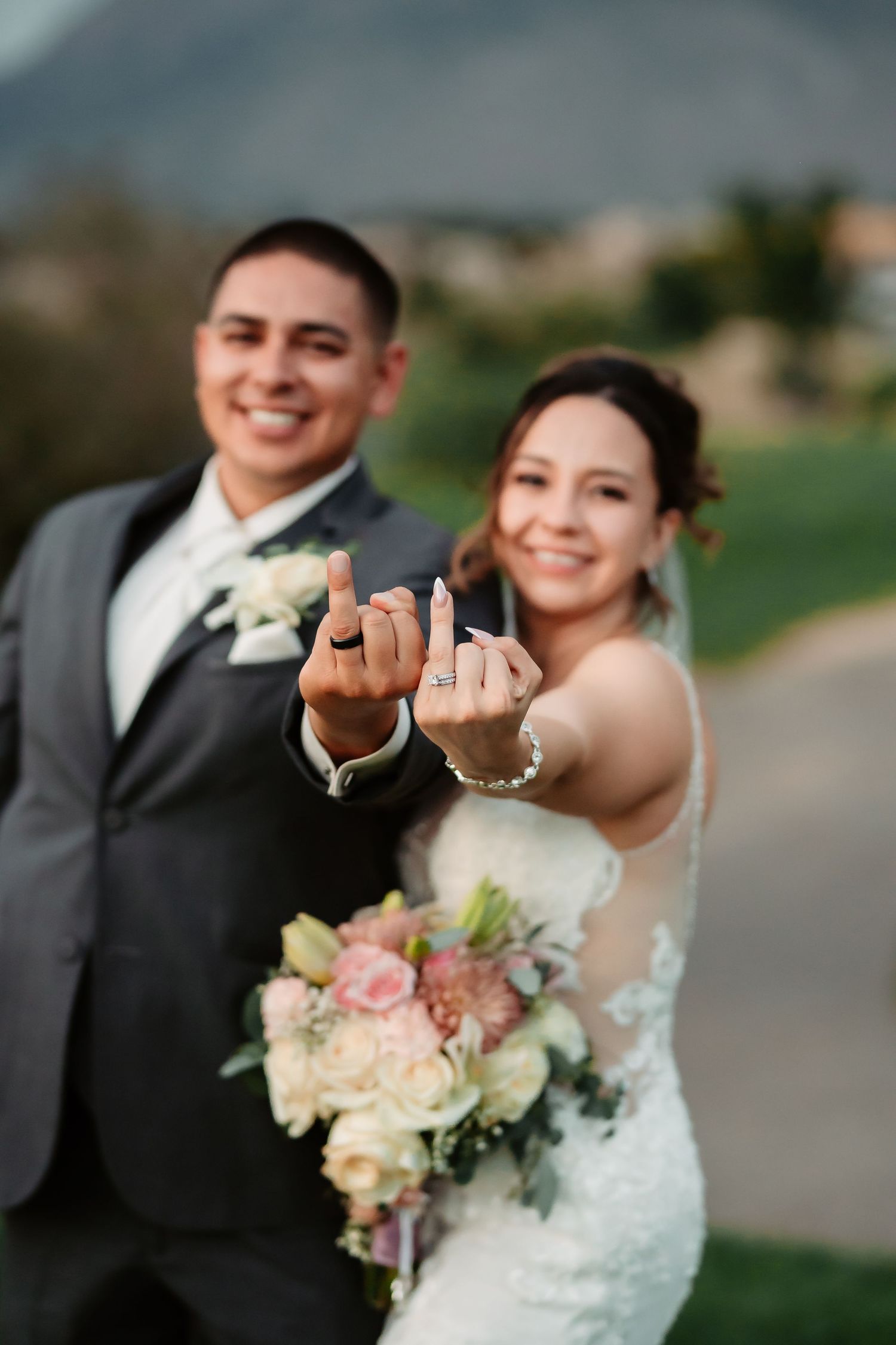 Happy newlyweds showing off their wedding rings with joyful expressions on a golf course.