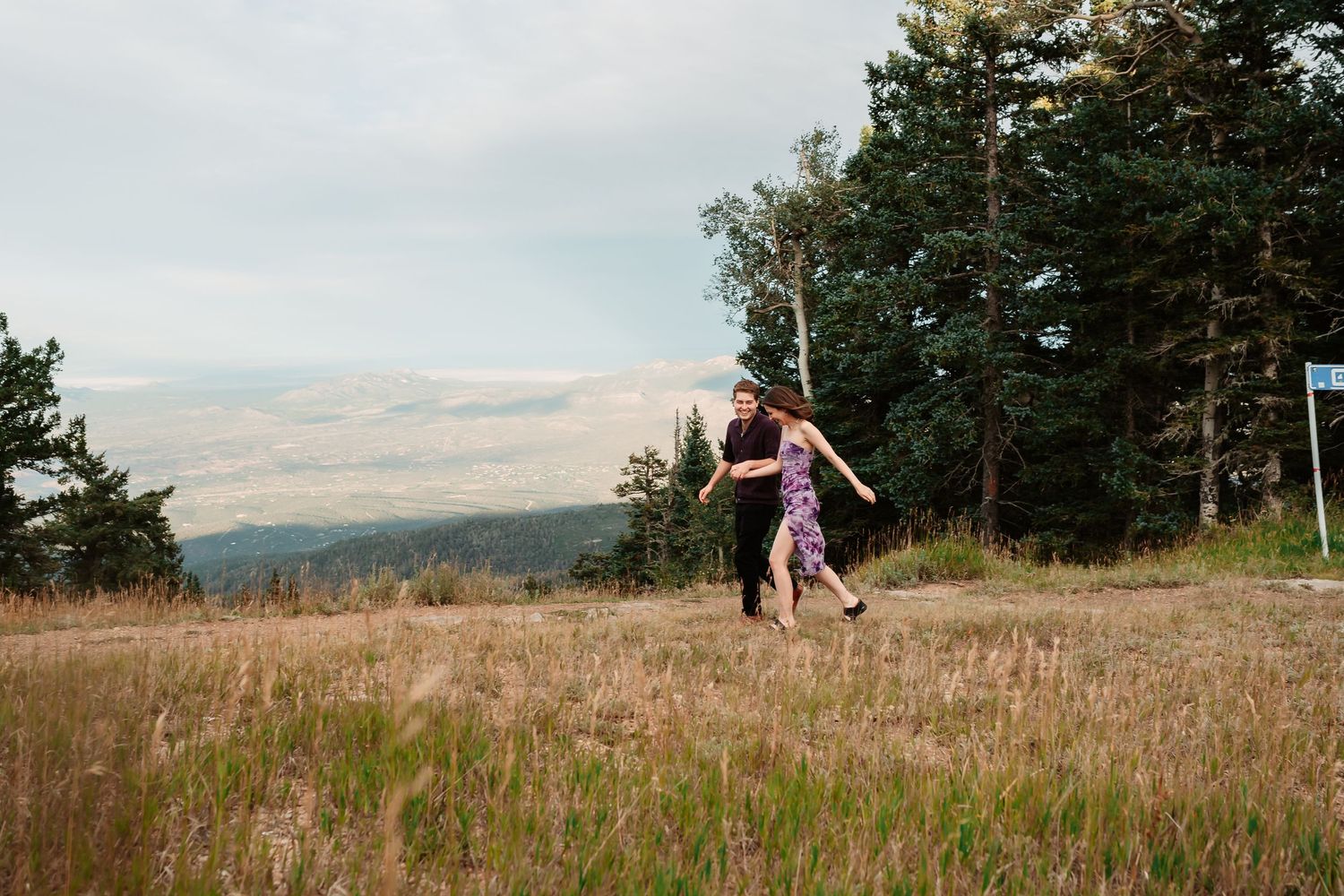 A figure in a purple dress twirls joyfully in a mountain meadow at sunset.