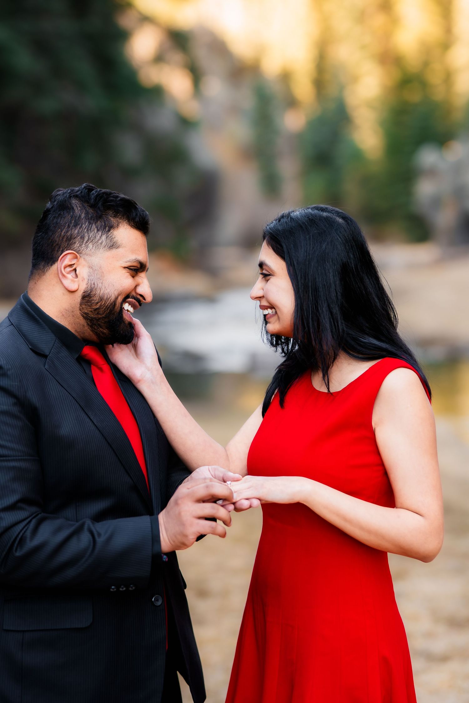 A couple shares a tender moment outdoors as a ring is presented during a romantic proposal.