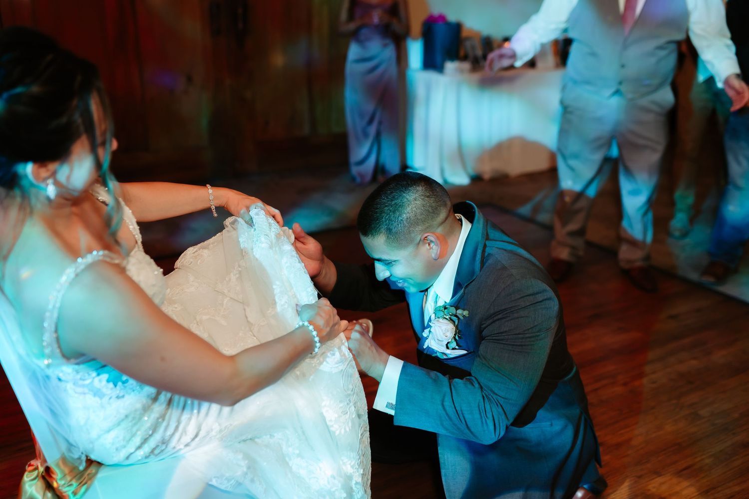 A playful wedding tradition moment on the dance floor with guests watching.