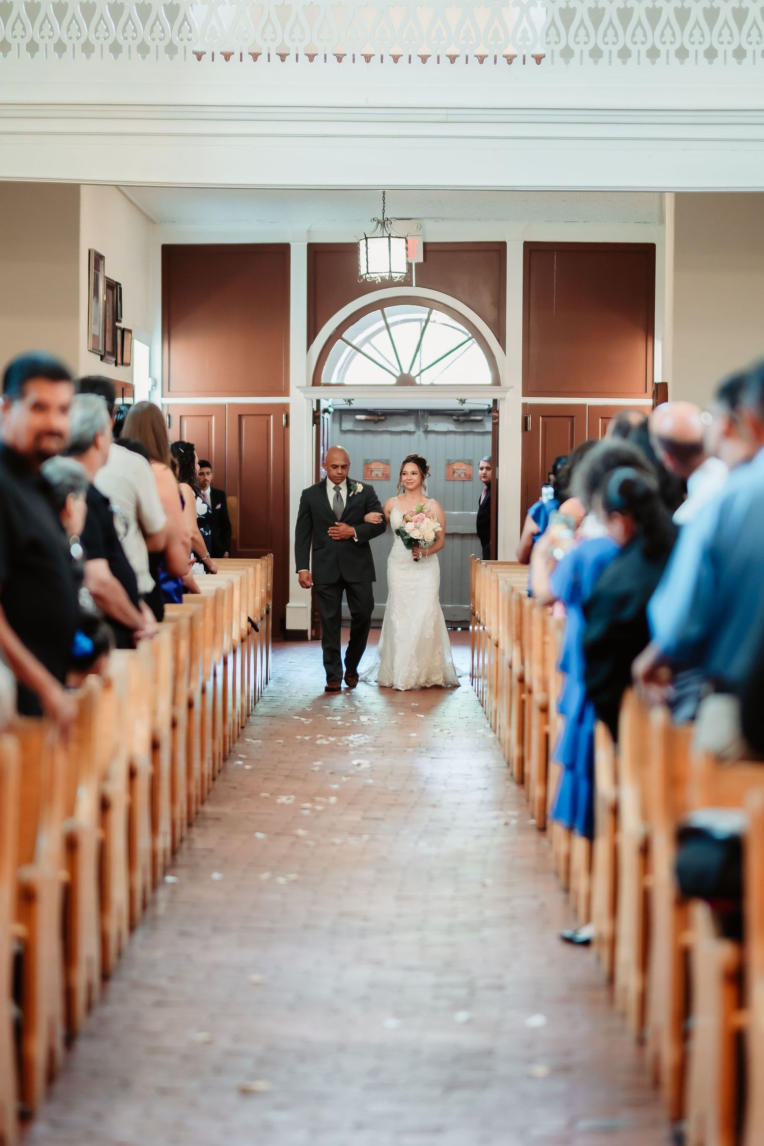 Wedding guests seated in wooden church pews during a ceremony.