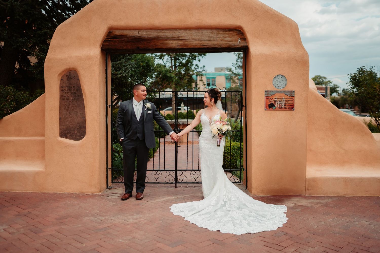 Silhouette of couple on wedding day walking away from camera at blush-colored stucco venue with palm trees.