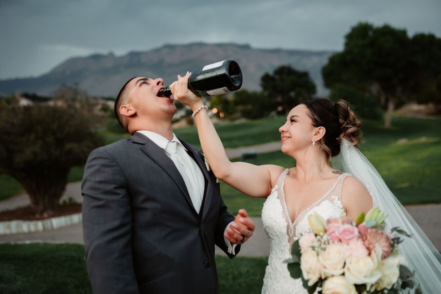 Joyful wedding celebration on a green hillside with mountains in the background.