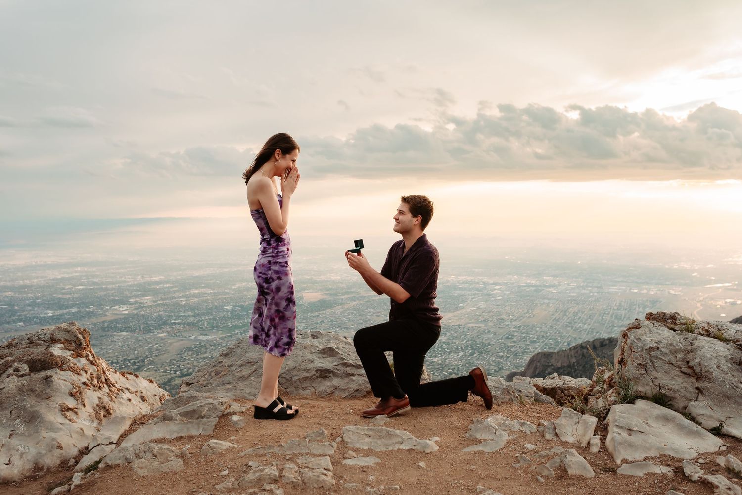 A scenic mountain top proposal at sunset with dramatic coastal views in the background.