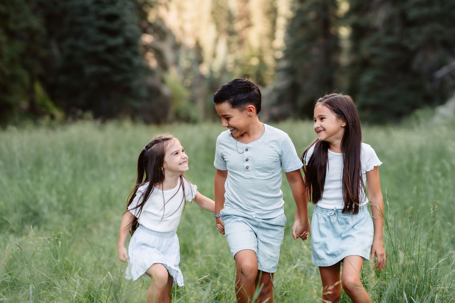 Group in white outfits playing and walking together in a lush green meadow during golden hour.
