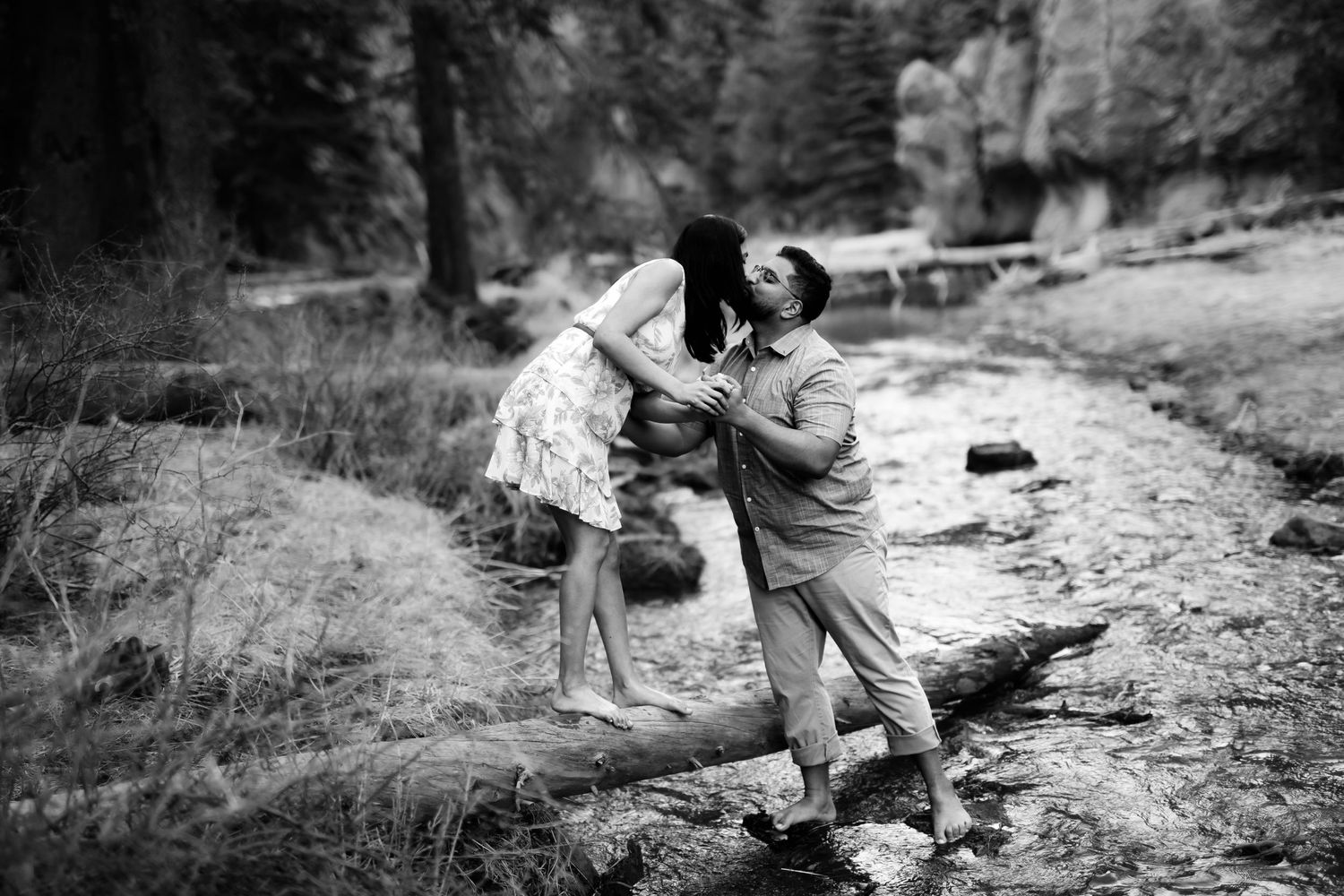 A couple dances joyfully together on rocky terrain in a black and white outdoor setting.