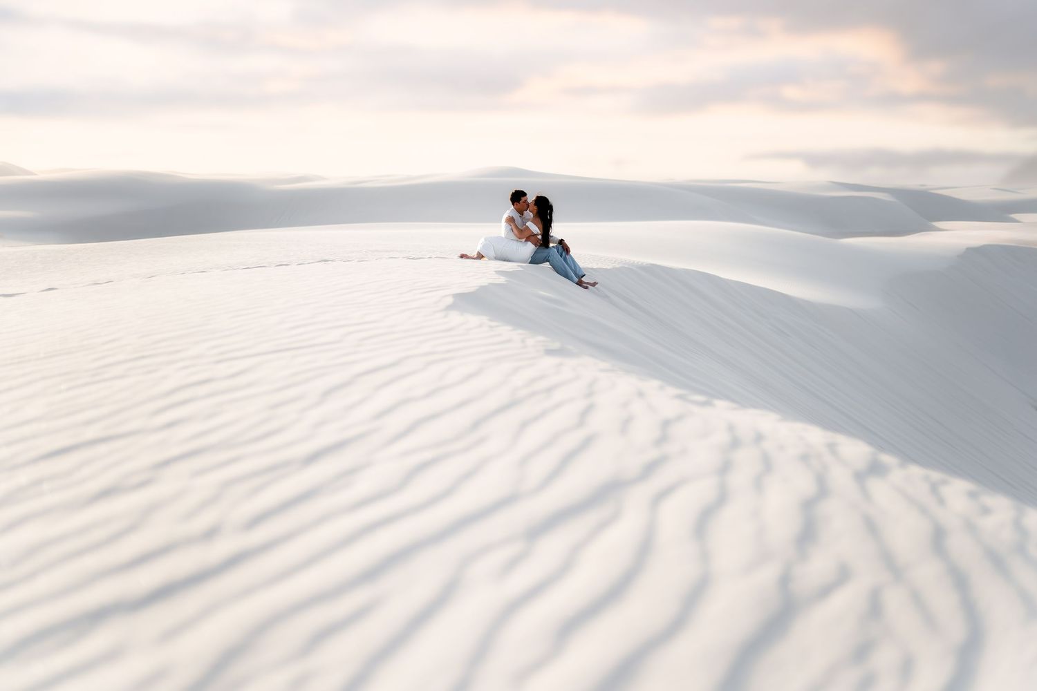A skier carves through pristine white snow dunes against a cloudy sky backdrop.