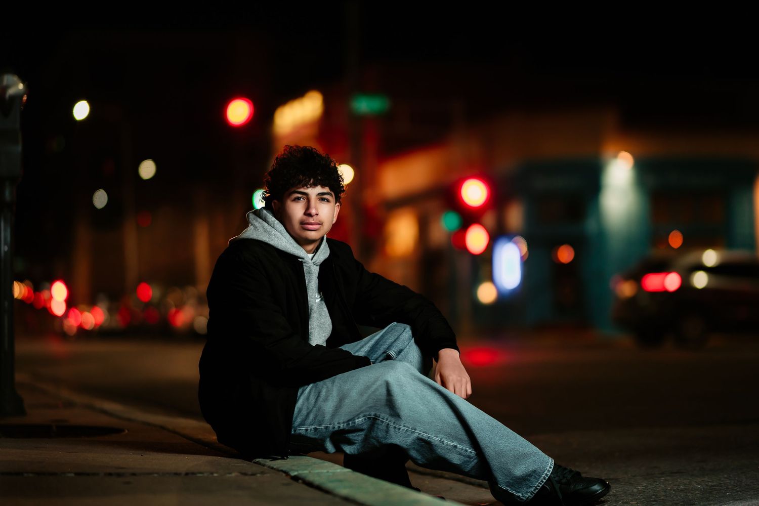 Person sits in car at night with city lights glowing in the background creating moody urban atmosphere.