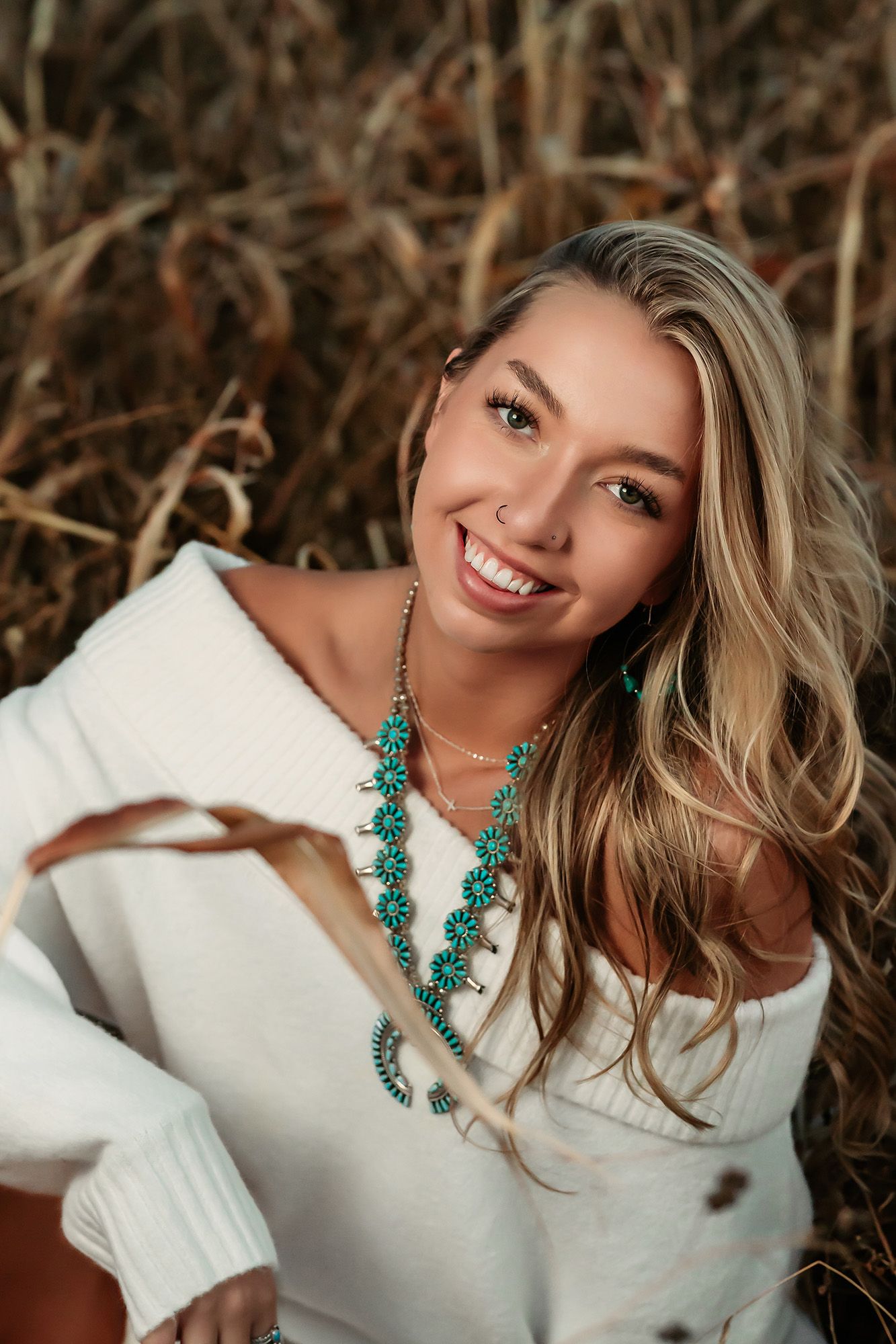 A series of four portrait photos showing someone wearing a white sweater and striking turquoise statement necklace.