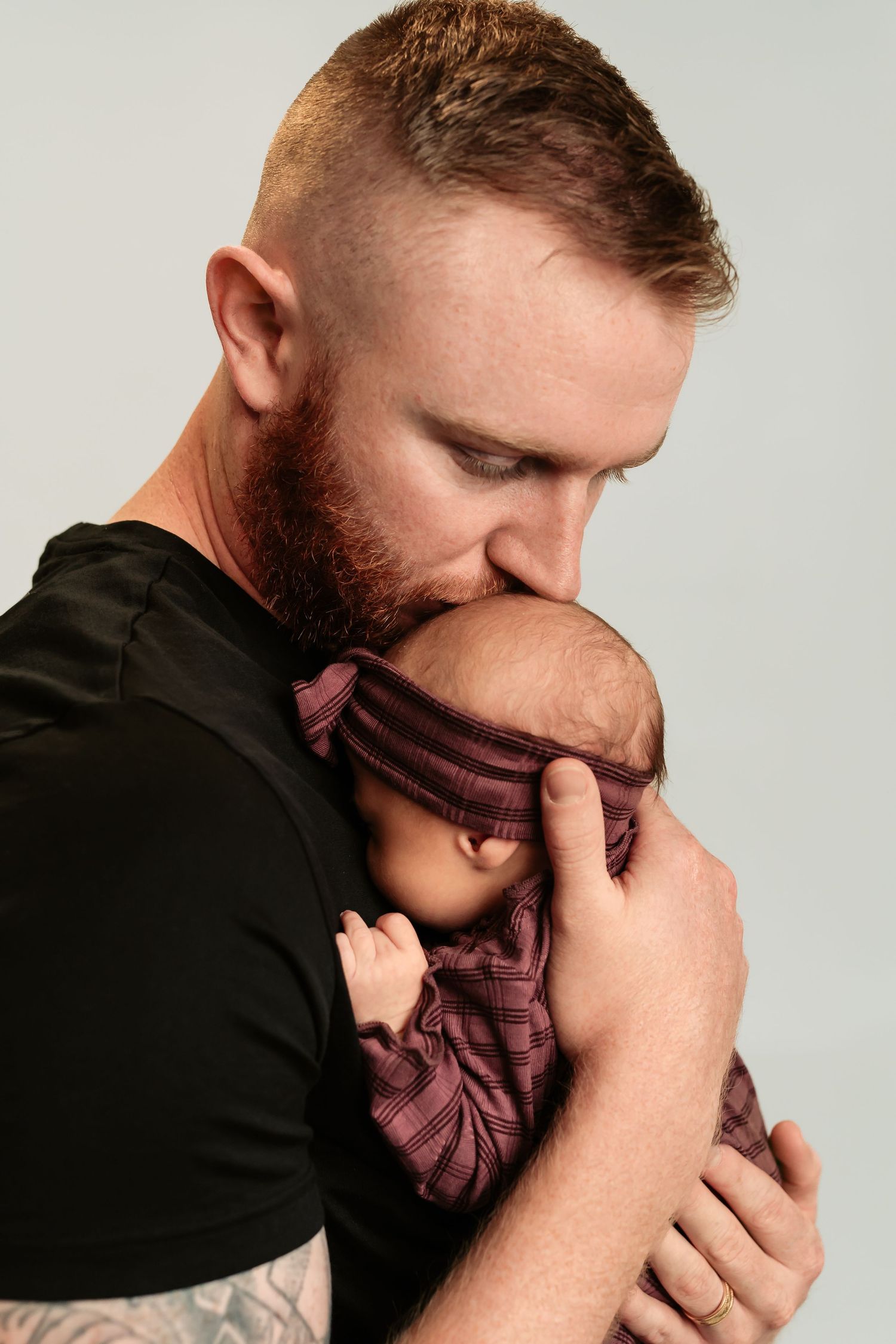 Close-up series showing a person in a black shirt holding and kissing a mauve colored fabric against dark background.