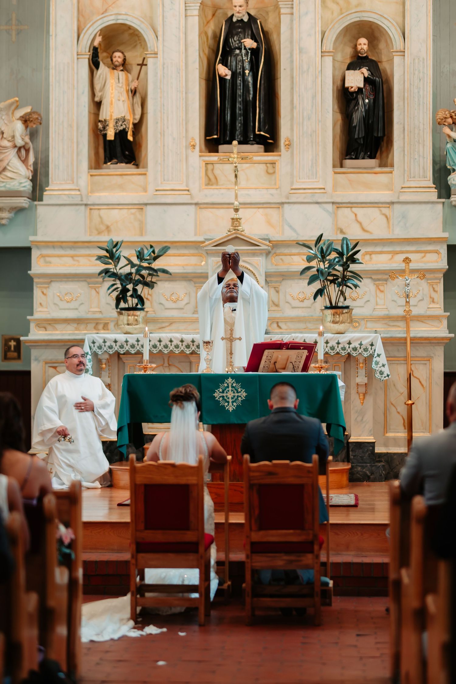 Church altar decorated with plants and religious icons during wedding ceremony.