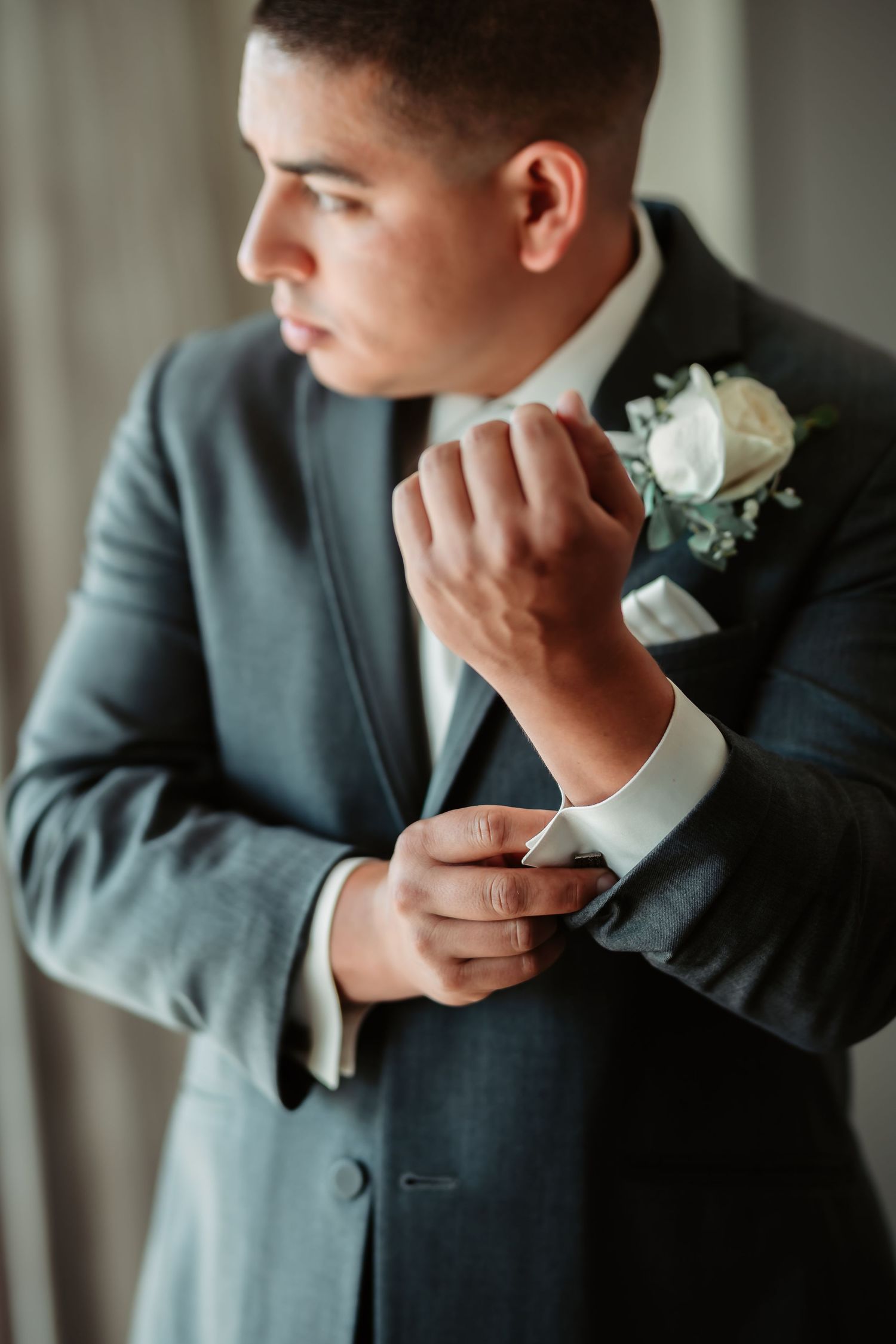 Close-up series showing formal suit details with white boutonniere in contemplative poses.