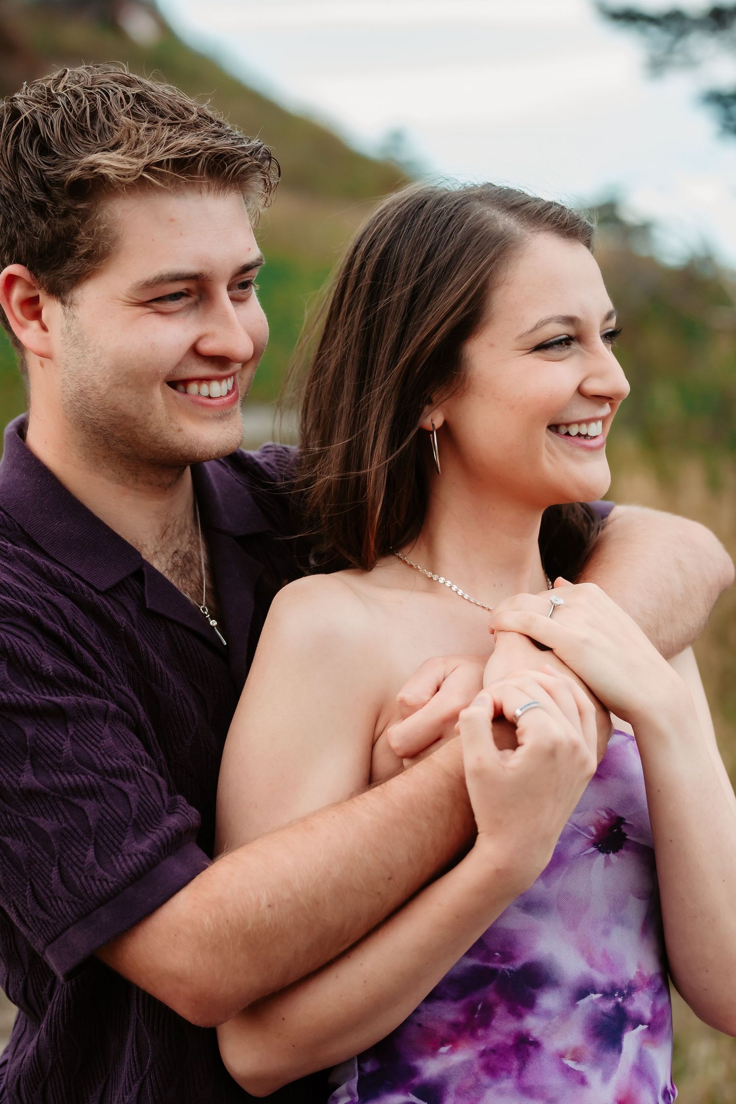 A couple laughing and embracing while enjoying a mountain sunset together.