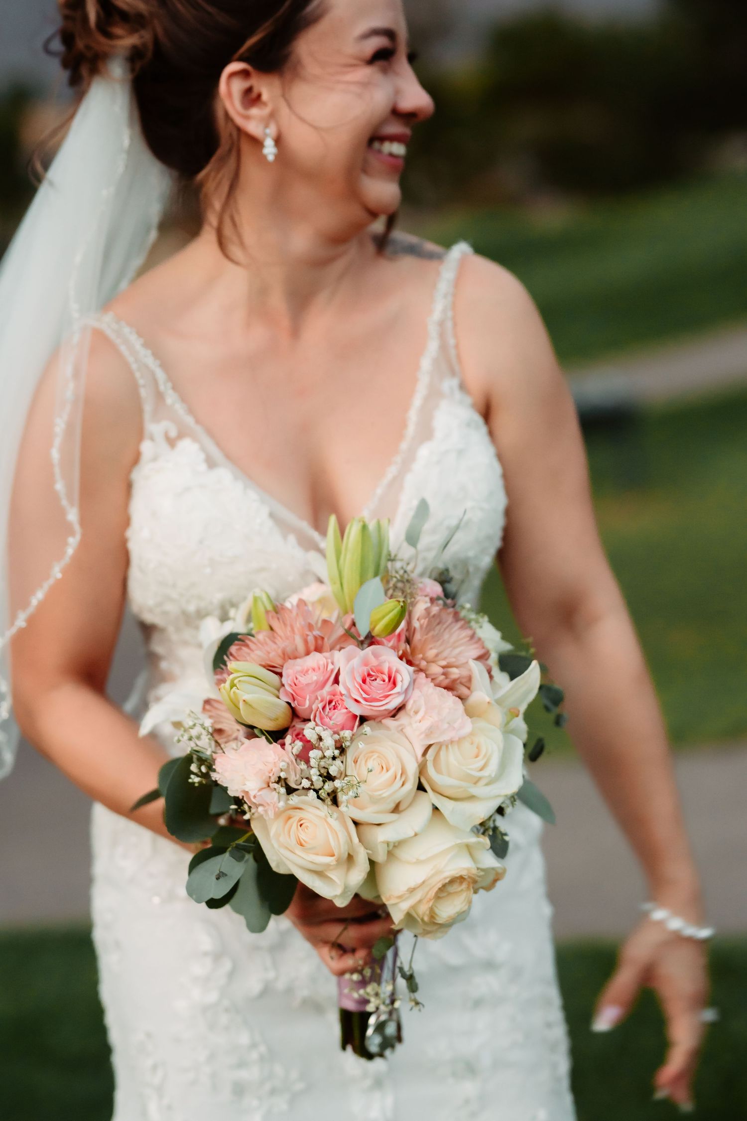 Romantic bridal bouquet featuring roses and greenery against an elegant white dress.