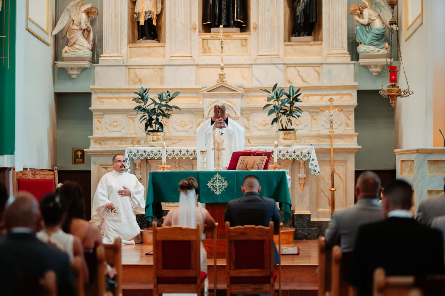 Interior view of ornate Catholic church altar with cream and mint green decor.