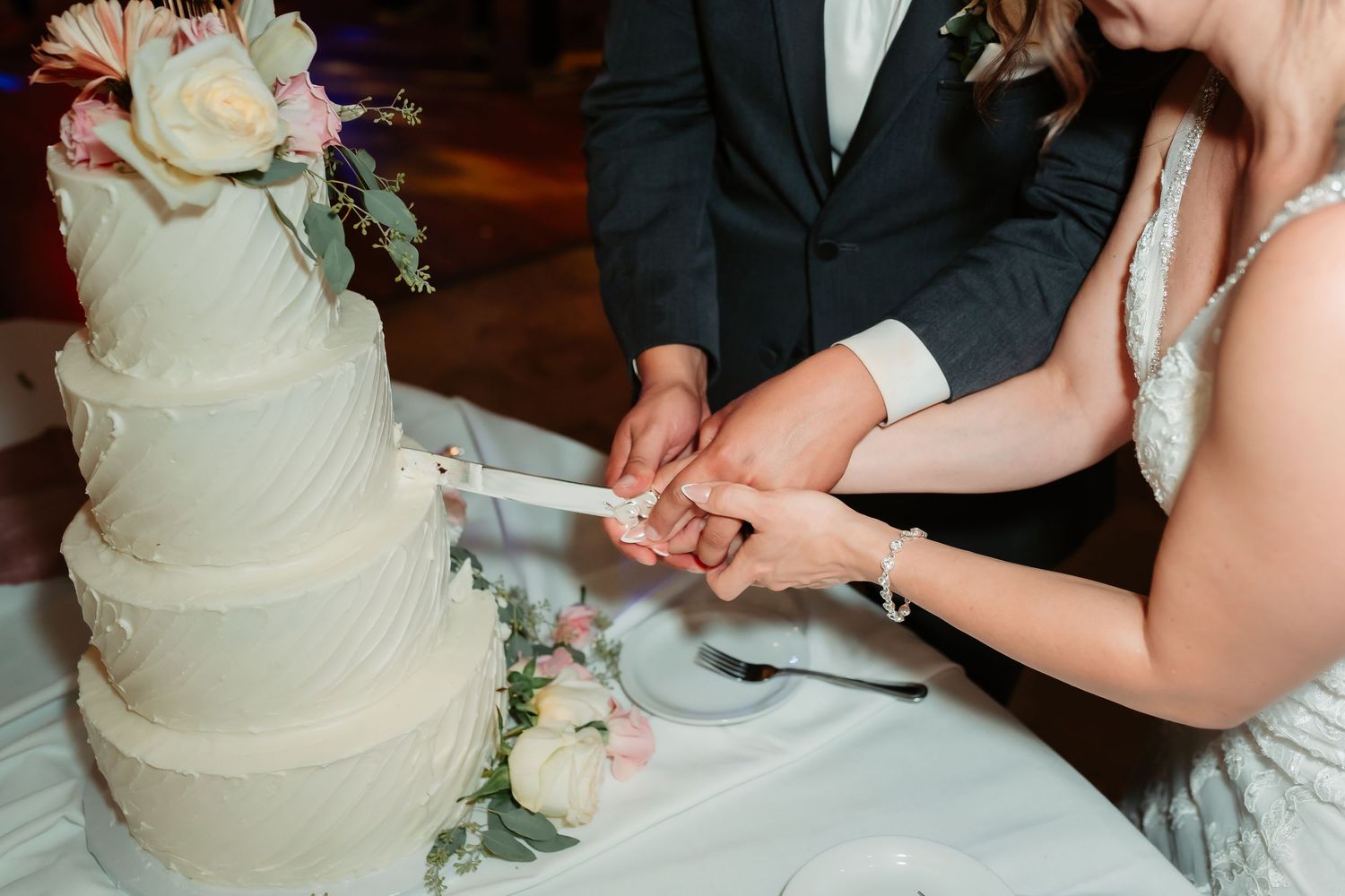 Wedding cake decorated with delicate floral accents awaits cutting at the reception.