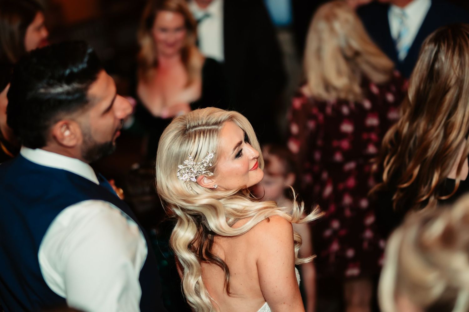 Guests dancing and celebrating at an elegant evening wedding reception with warm lighting and festive atmosphere.