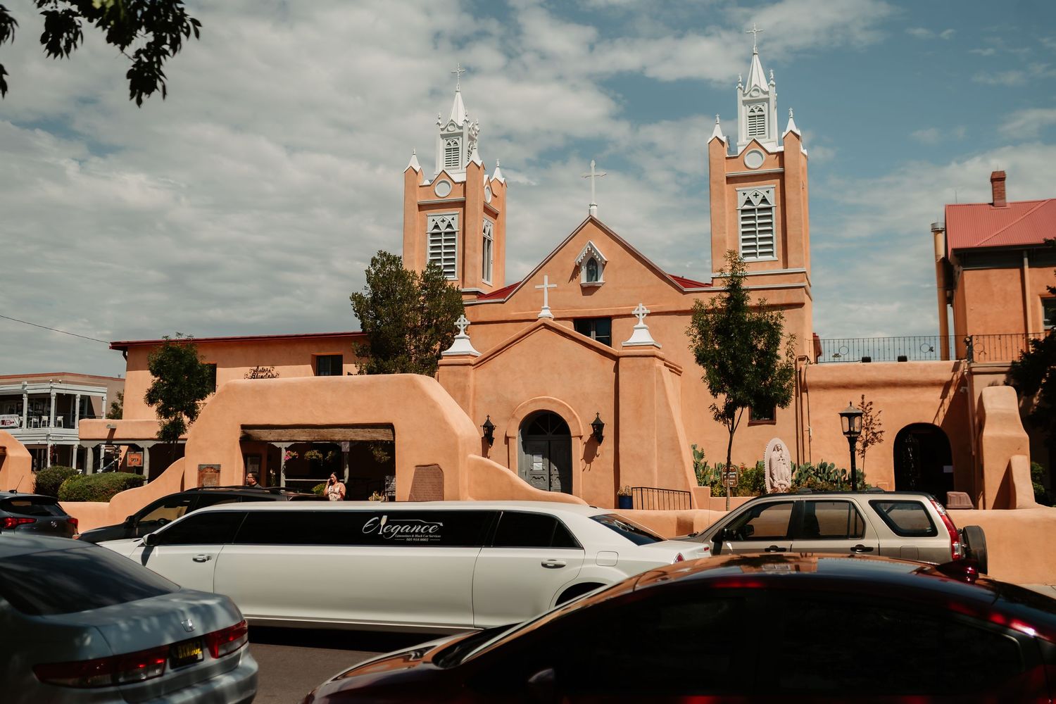 A series of terracotta colored church or mission buildings with white trim under a bright blue sky.