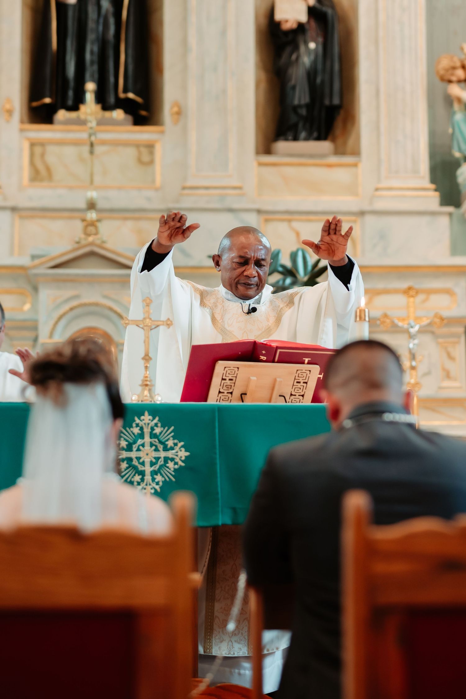 Religious service in an ornate church with wooden pews and decorative architectural details.