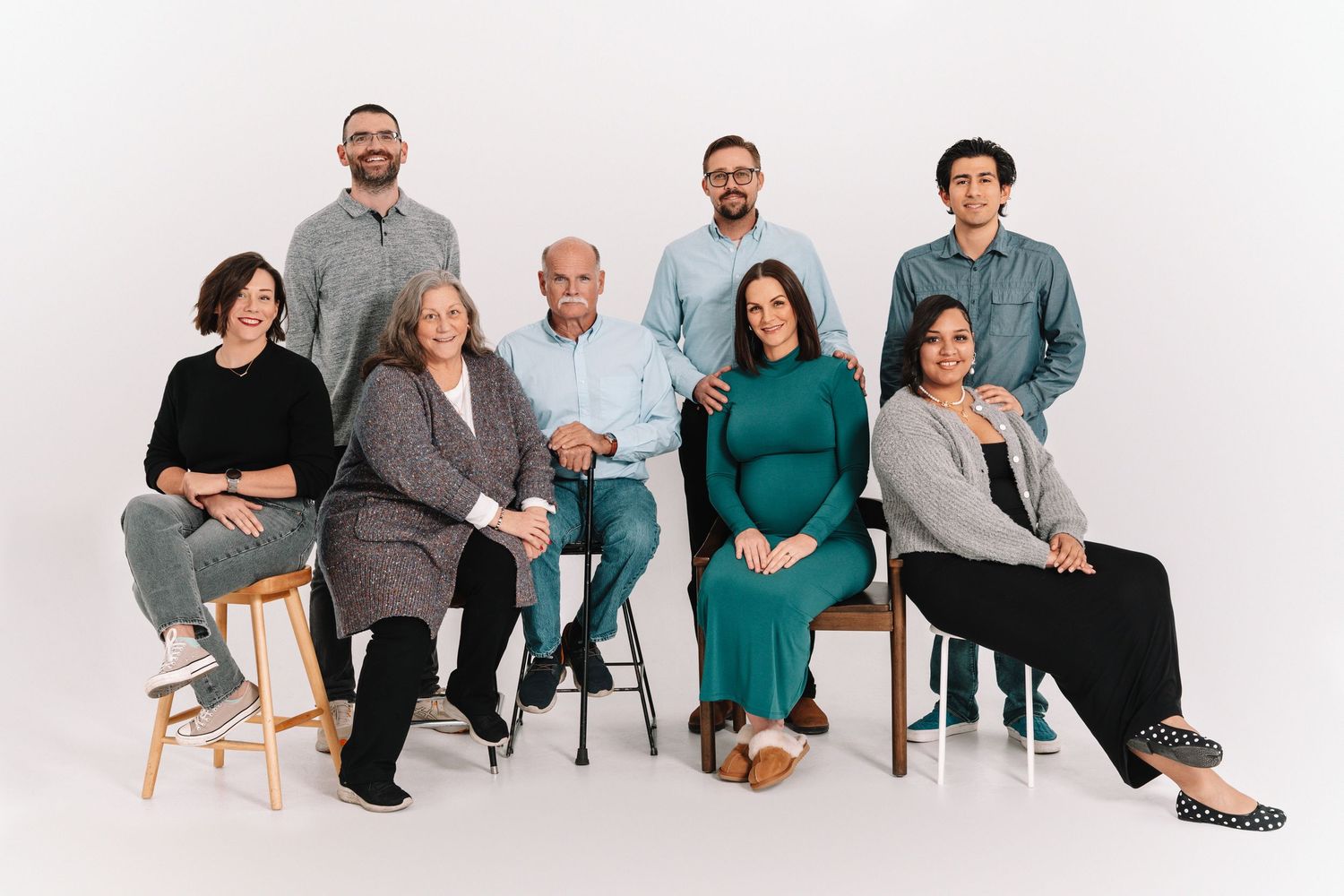A group of people sitting in modern chairs arranged in a horizontal line against a white background.