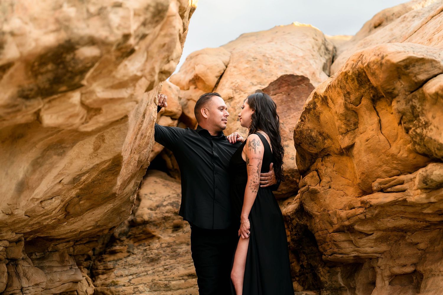 Romantic couple sharing an intimate moment surrounded by warm golden sandstone rocks outdoors.