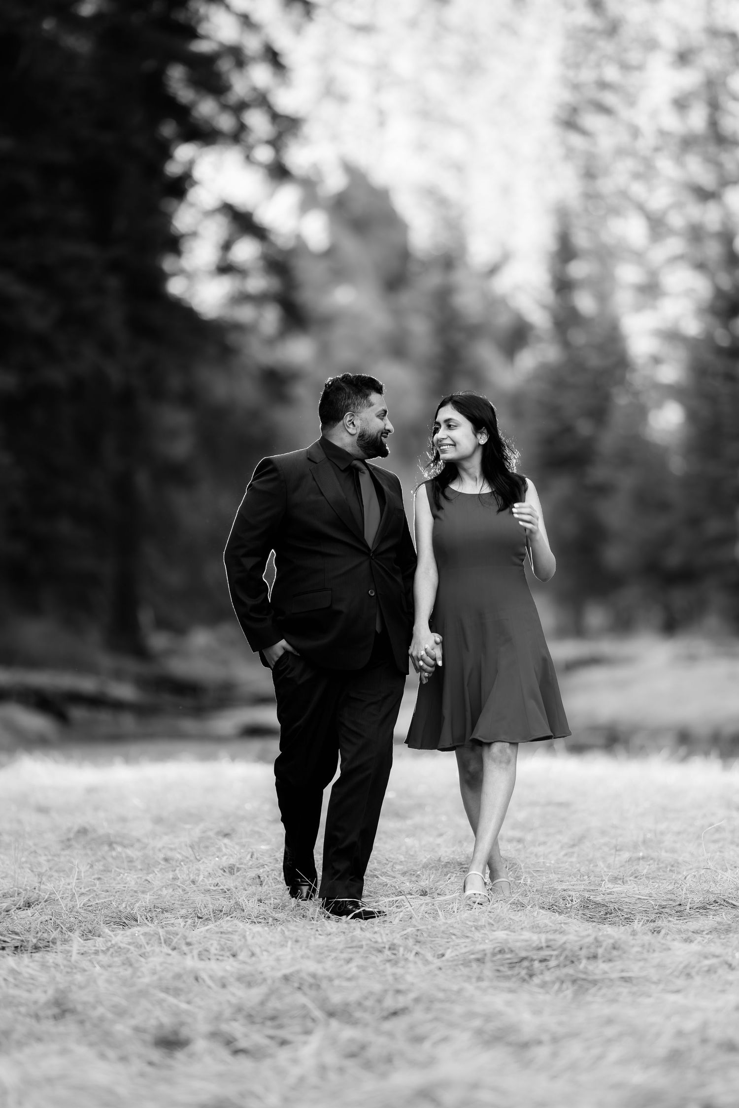 A couple takes a romantic stroll together through a misty forest clearing.