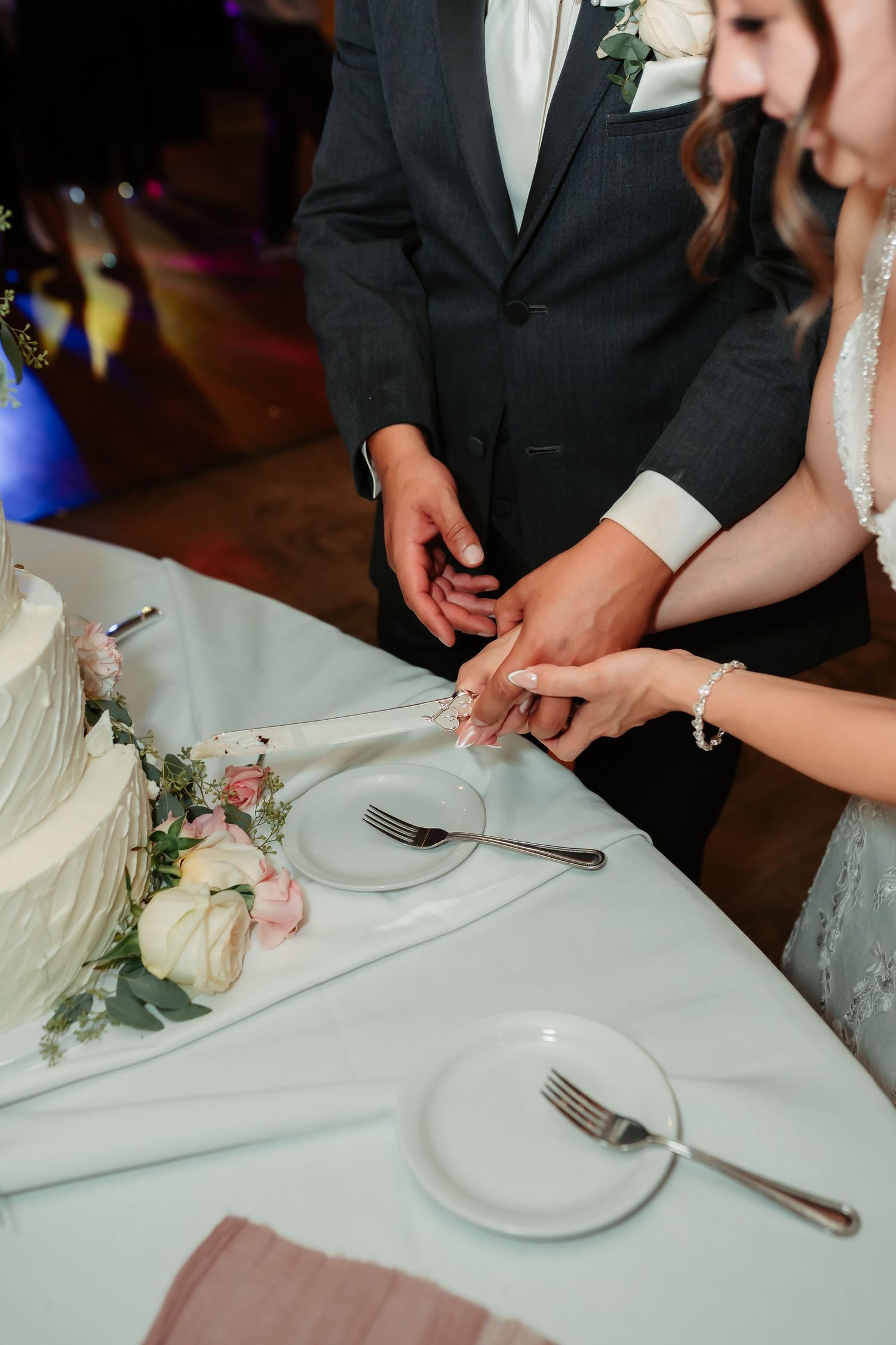 A newlywed couple signs their marriage license at a table while holding pens during their wedding reception ceremony.