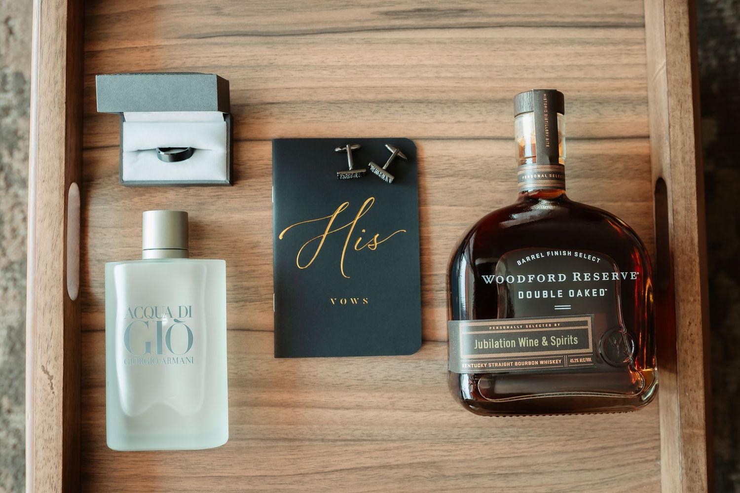 Elegant wedding invitation suite with whiskey bottle and dark moody styling on natural wood surface.