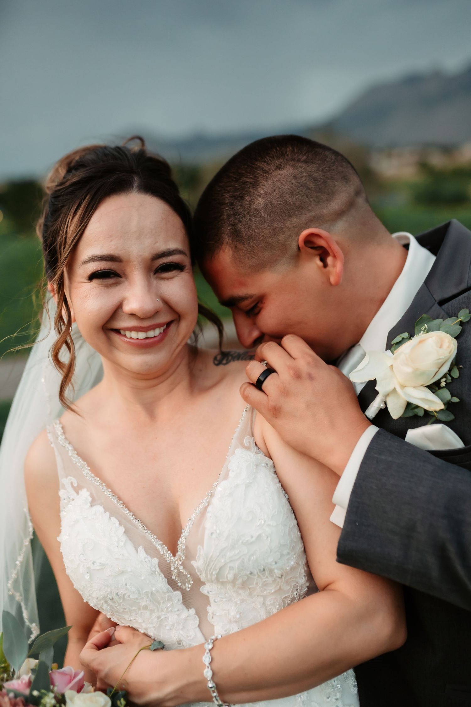 A joyful wedding portrait shows a couple sharing an intimate moment together with mountains in the background.