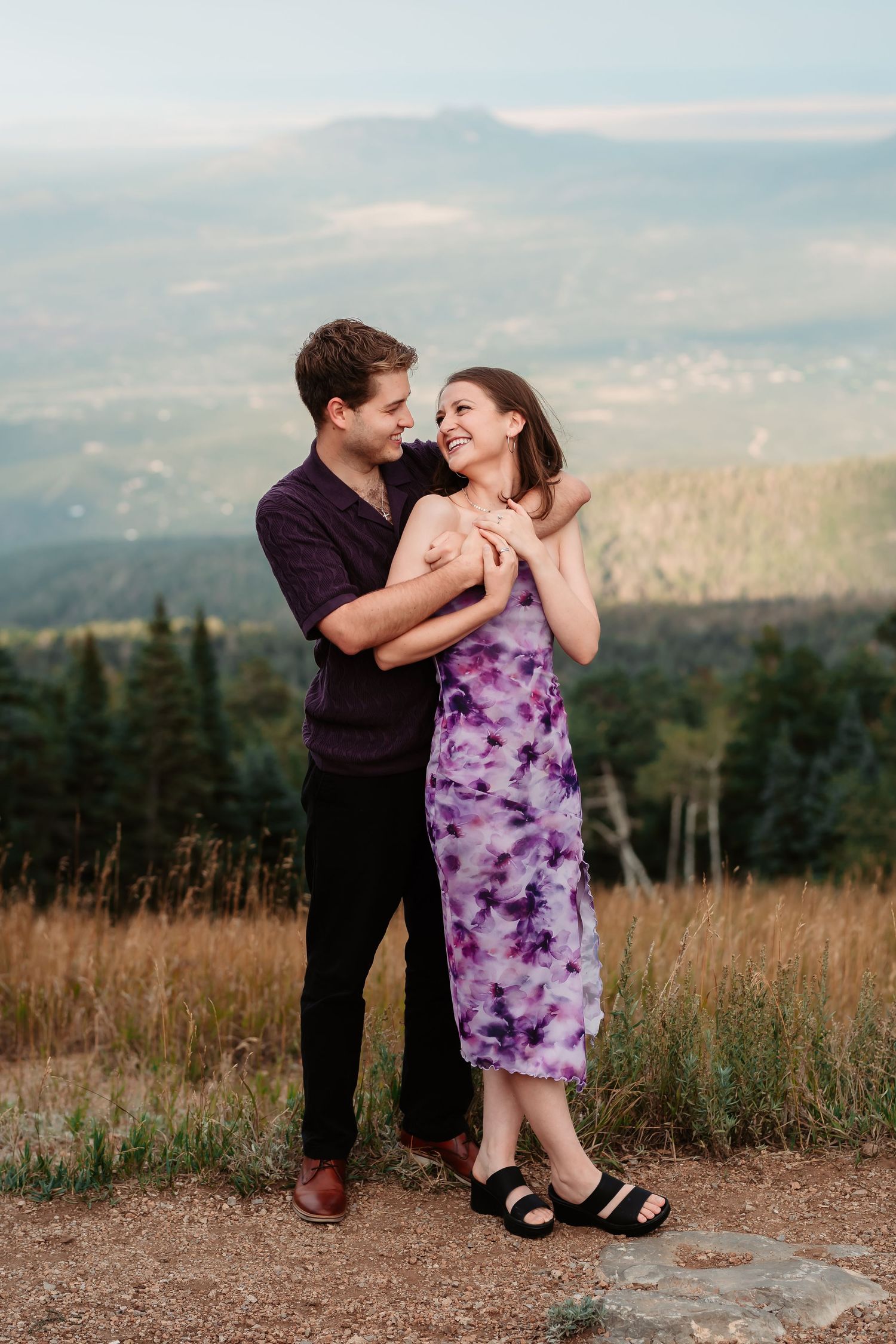 A couple sharing intimate moments on a mountain path surrounded by tall grass.