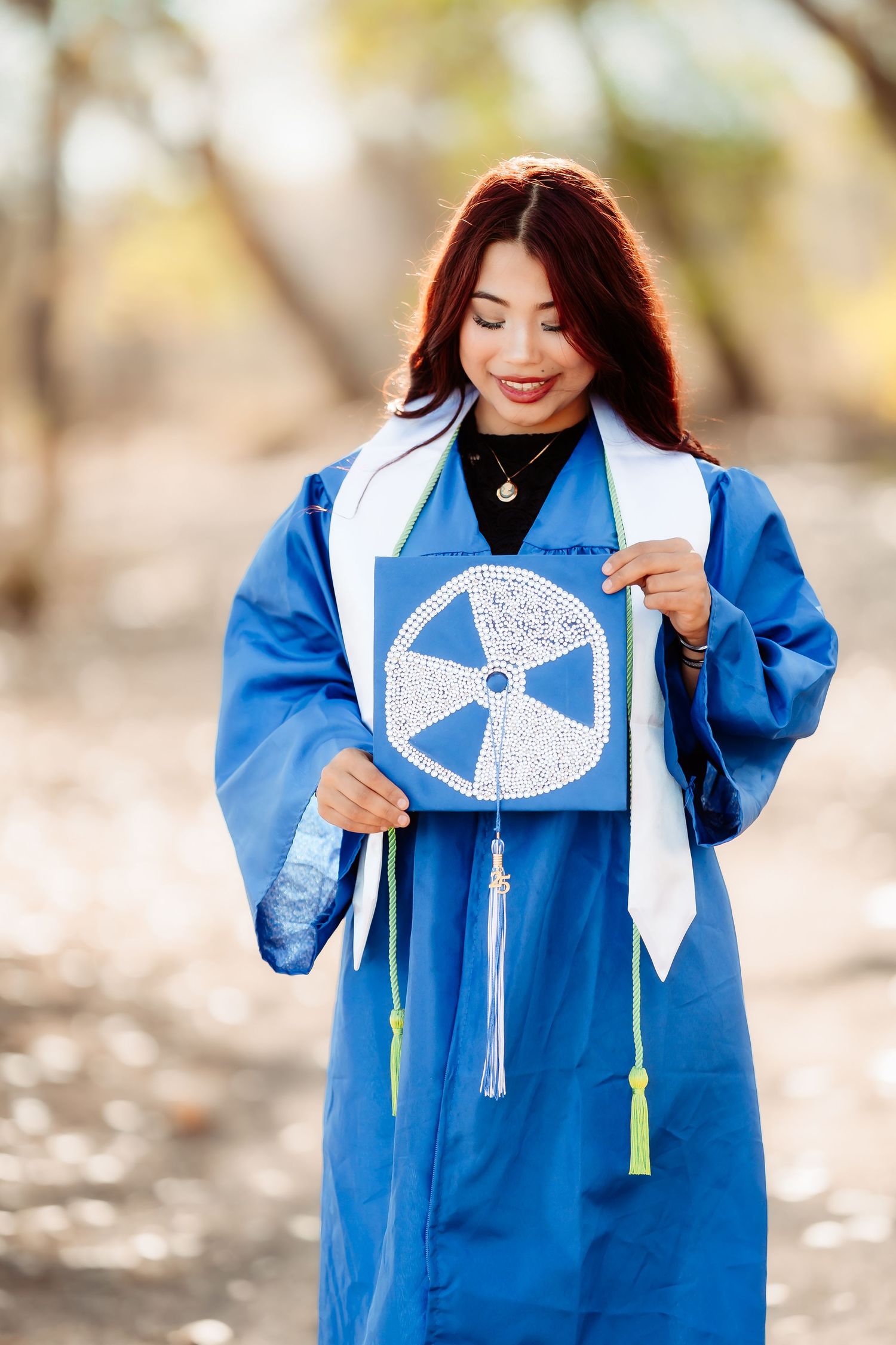 Woman wearing bright blue traditional Native American dress with white embroidered details smiles outdoors.