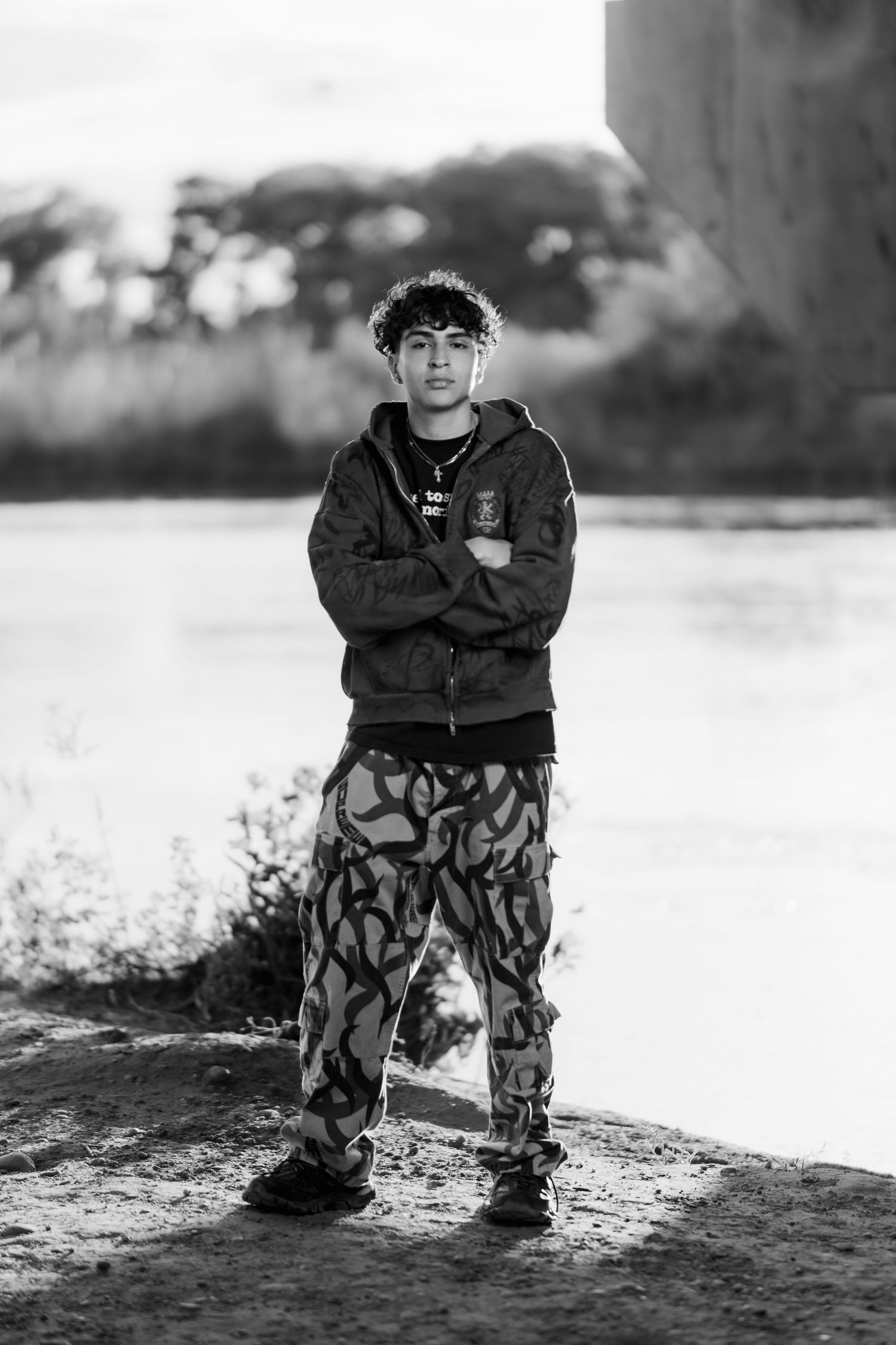 Black and white portrait showing urban streetwear with camo pants in natural setting.