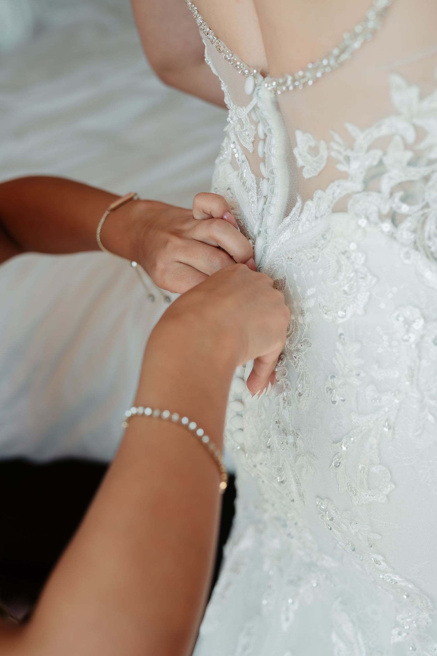 A person wearing an elegant white lace wedding dress and delicate pearl jewelry.