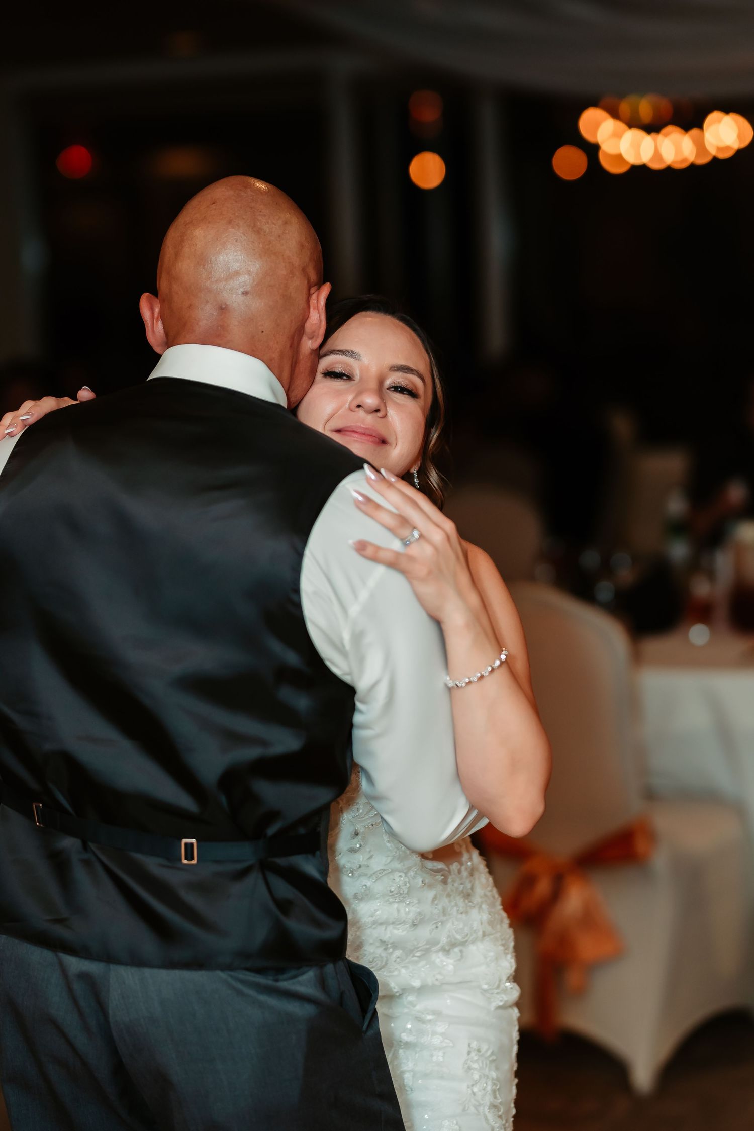 A tender moment during a wedding dance showcasing partners embracing on the dimly lit dance floor.