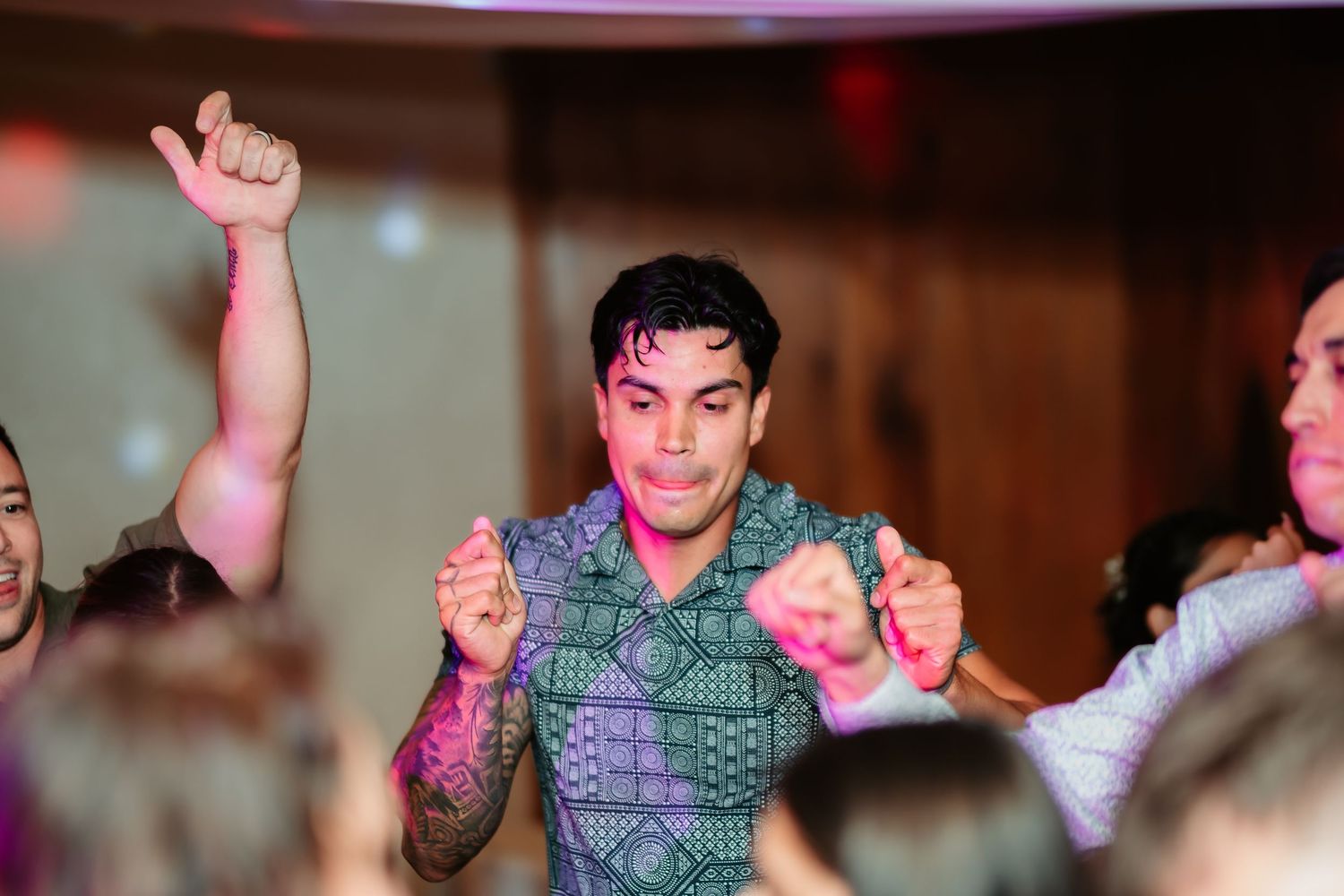 Energetic wedding guests raise their arms in celebration during an upbeat dance number.