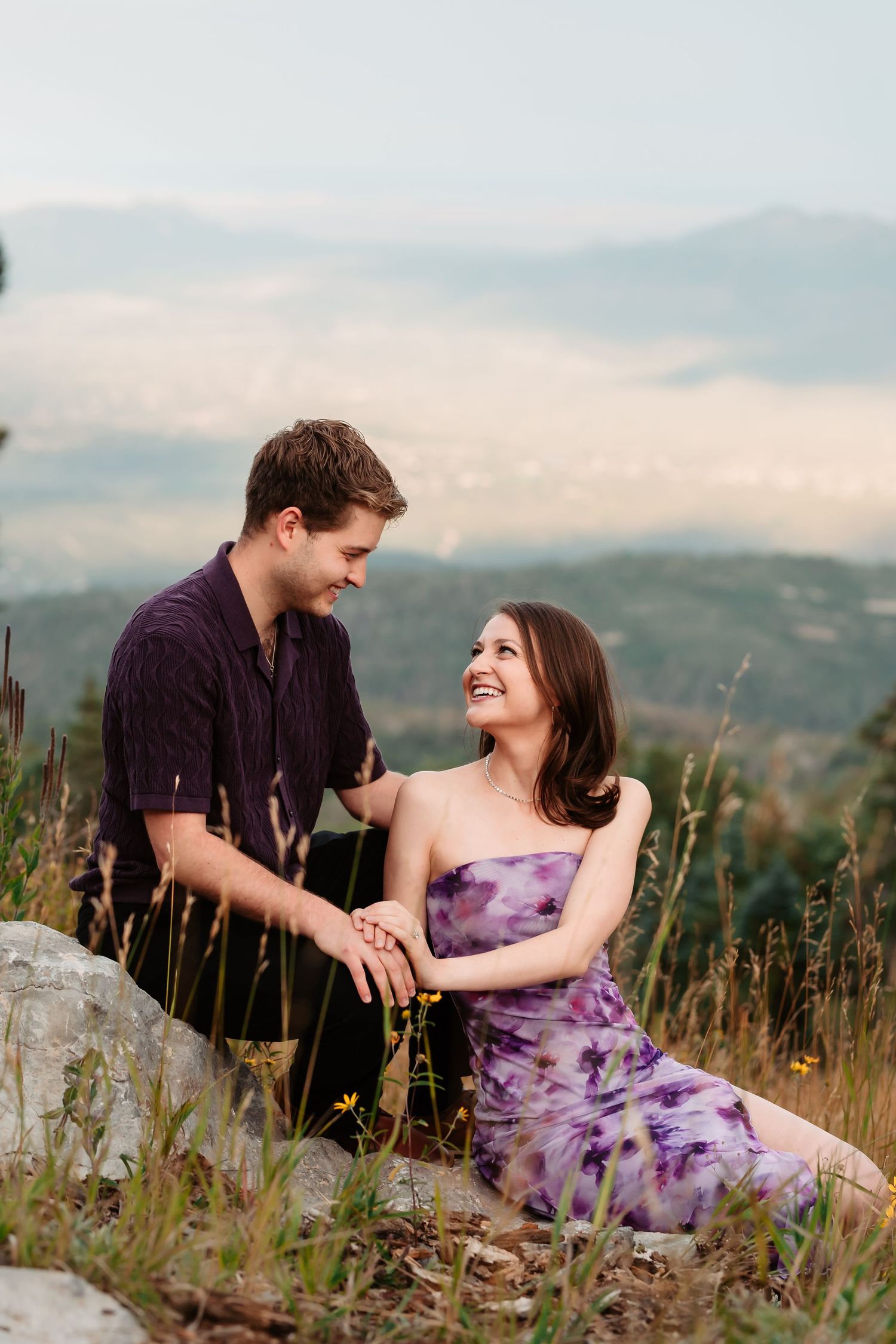 A couple relaxing in a wildflower meadow with mountain views in the background.