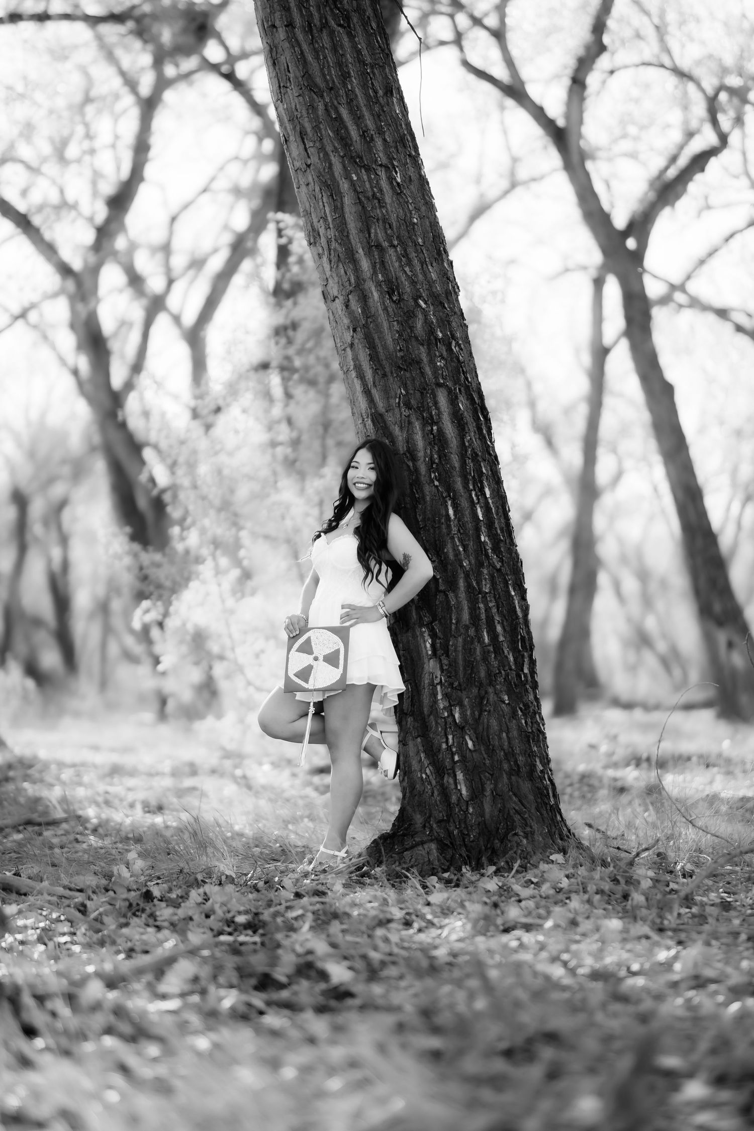 Black and white outdoor photography series featuring artistic poses near a large tree trunk.