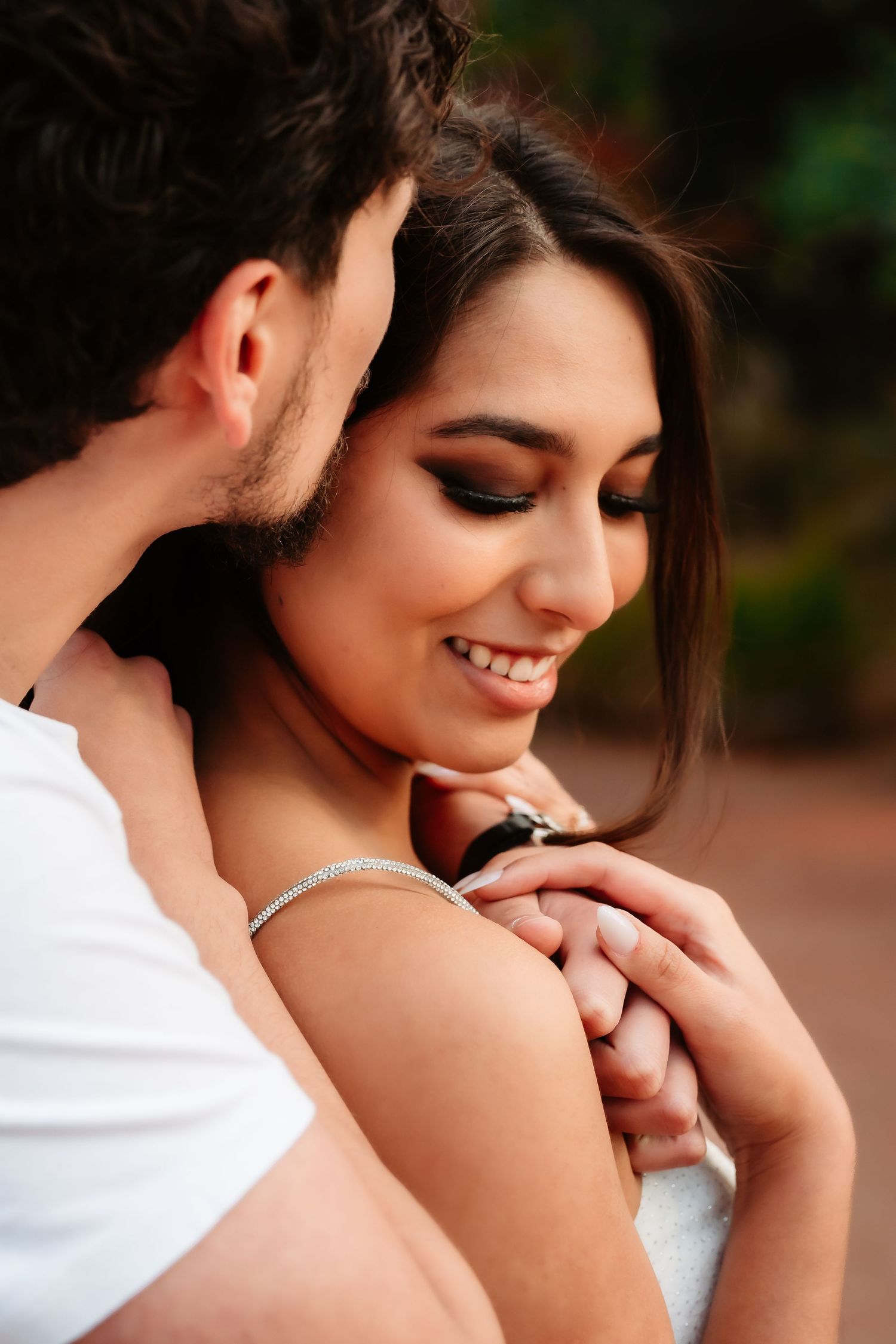 A romantic couple shares an intimate moment together outdoors in warm lighting.