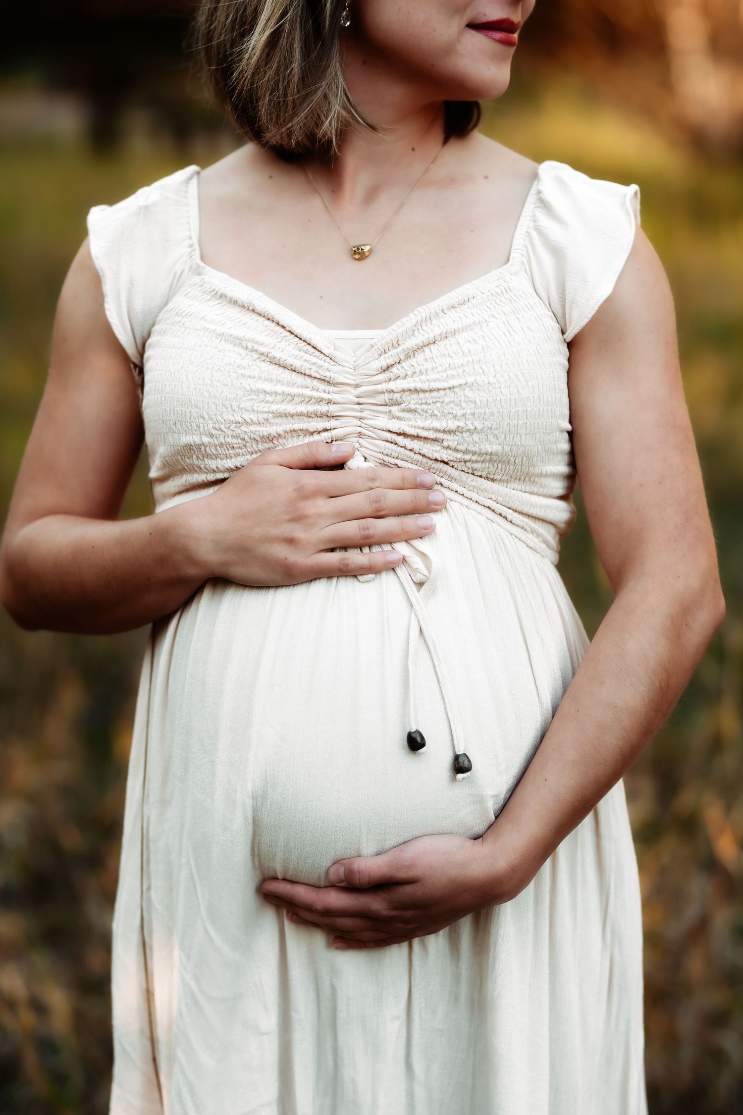 Series of intimate maternity poses showing hands placed lovingly across a white dress in natural light.
