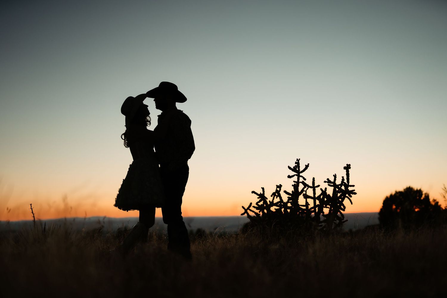 Silhouettes of people walking along a hilltop against a dramatic sunset sky.